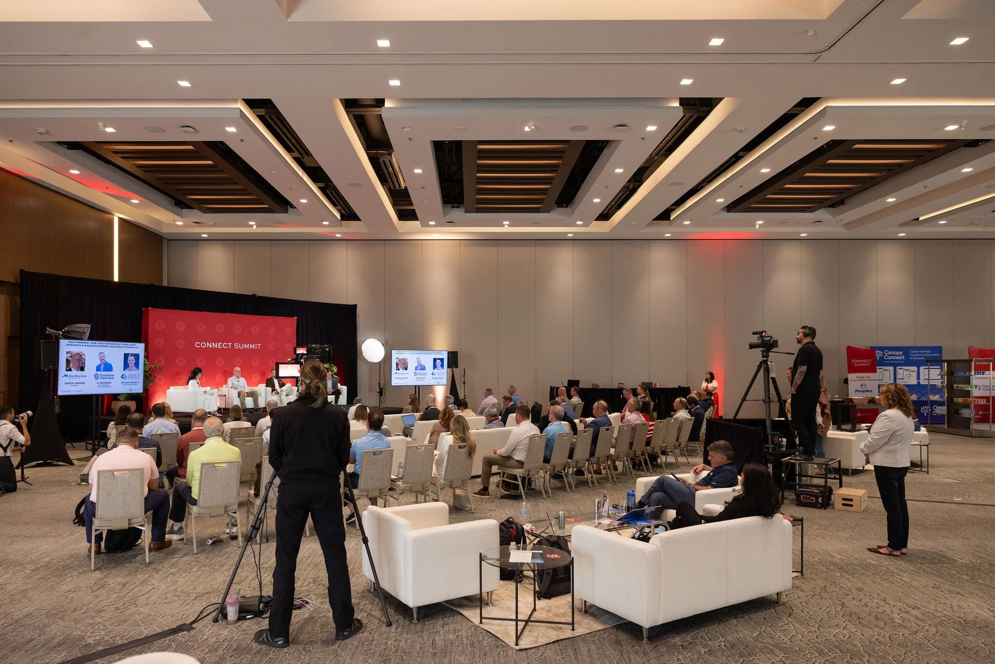 Hotel ballroom set up for a Connect Summit panel session with stage, screens and video crew