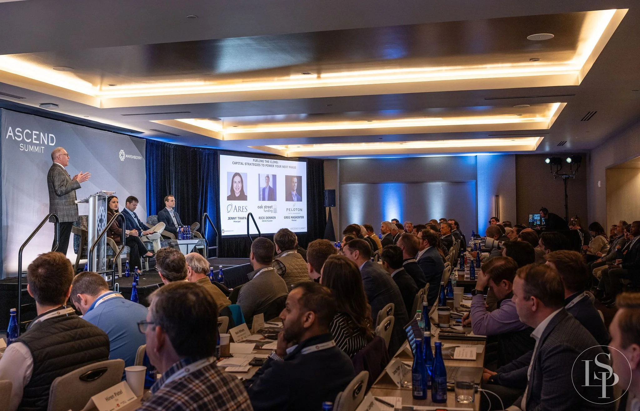 full room with attendees and panel of leadership speakers engaged event photo