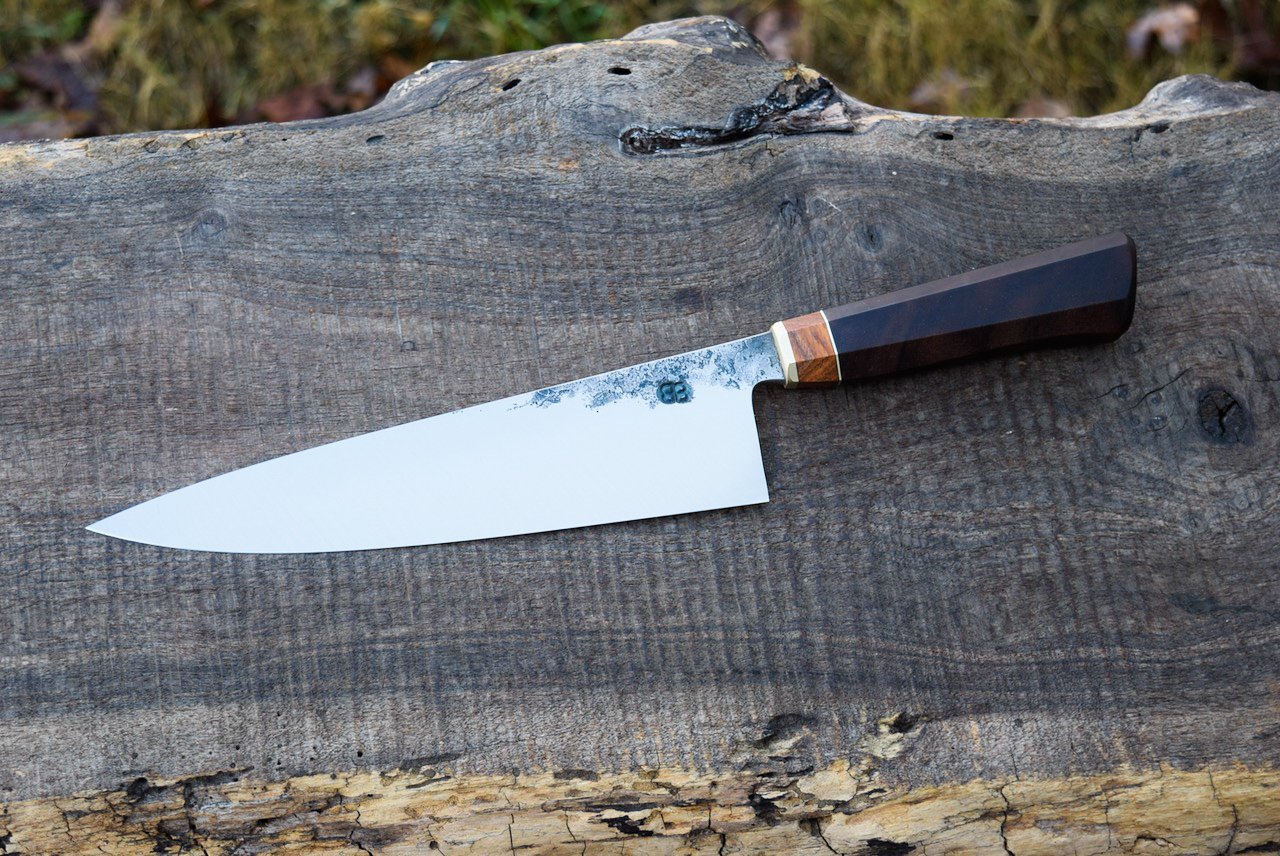  9.5” Hidden-Tang Chef with Forge Finish. Westernized Octagonal Walnut Handle with a Brass Faceplate and Cherry Burl and Bronze Spacers. 