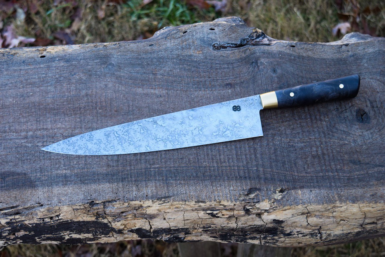  10.5” Full-Tang Chef with Forge Finish and Mustard Patina. Western Black Maple Handle with Brass Bolsters and Pins. 