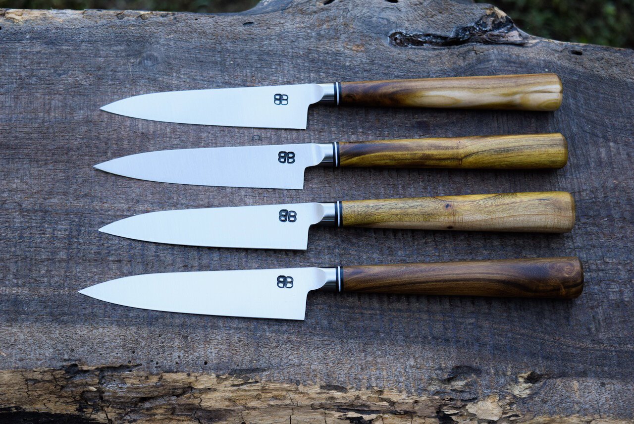  4.25” Integral Steak Knives. Oval Redbud Handles with Leather and Fiber Spacers. 