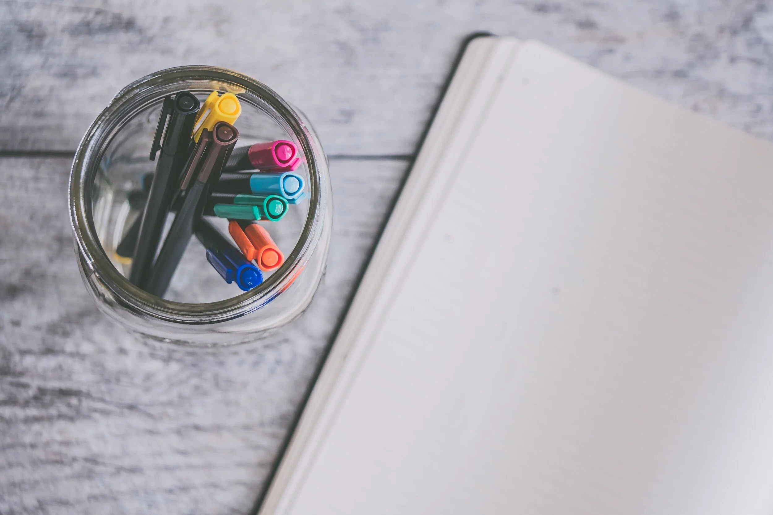 clear-glass-jar-filled-of-coloring-pens-beside-of-white-998592.jpg