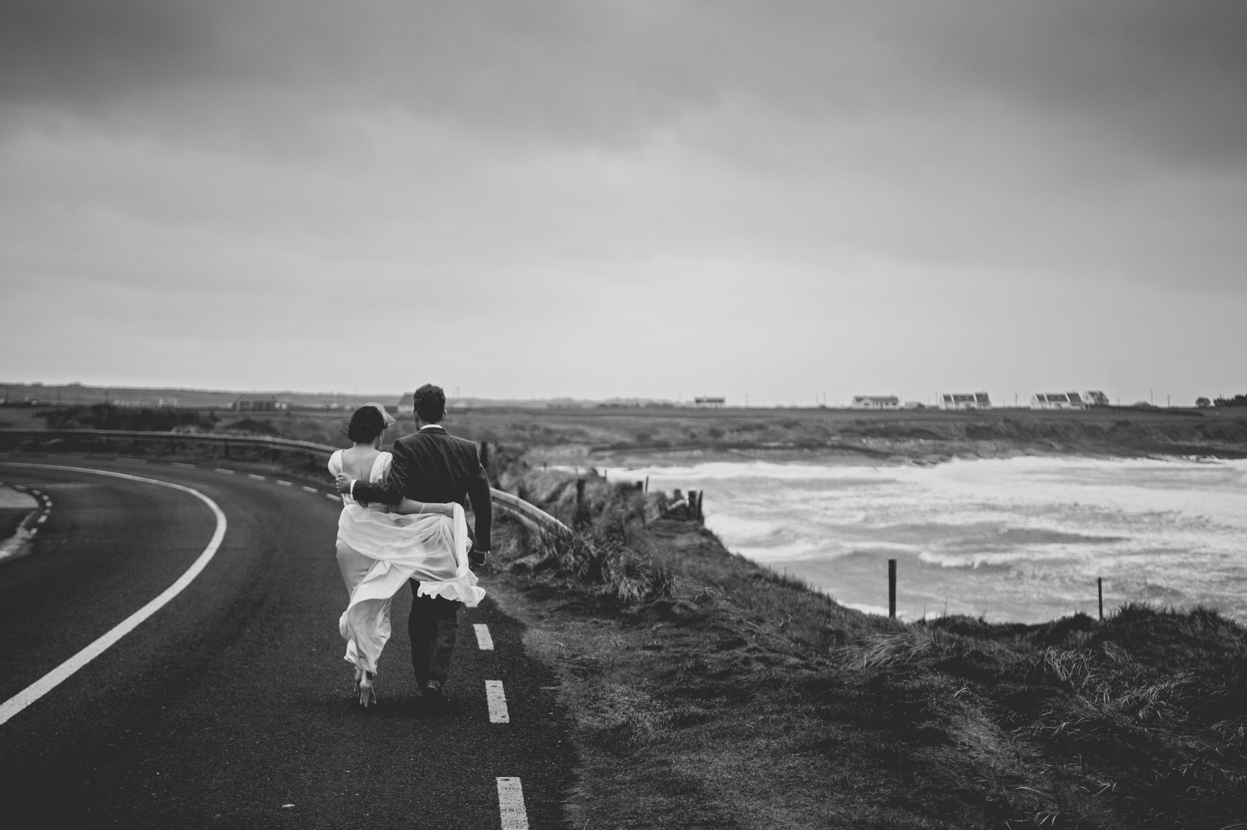 Wedding couple walking the coast road in Spanish Point