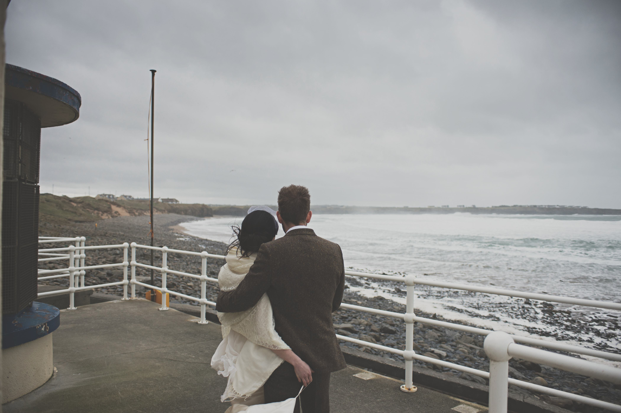 Wedding couple look out at sea, Spanish Point