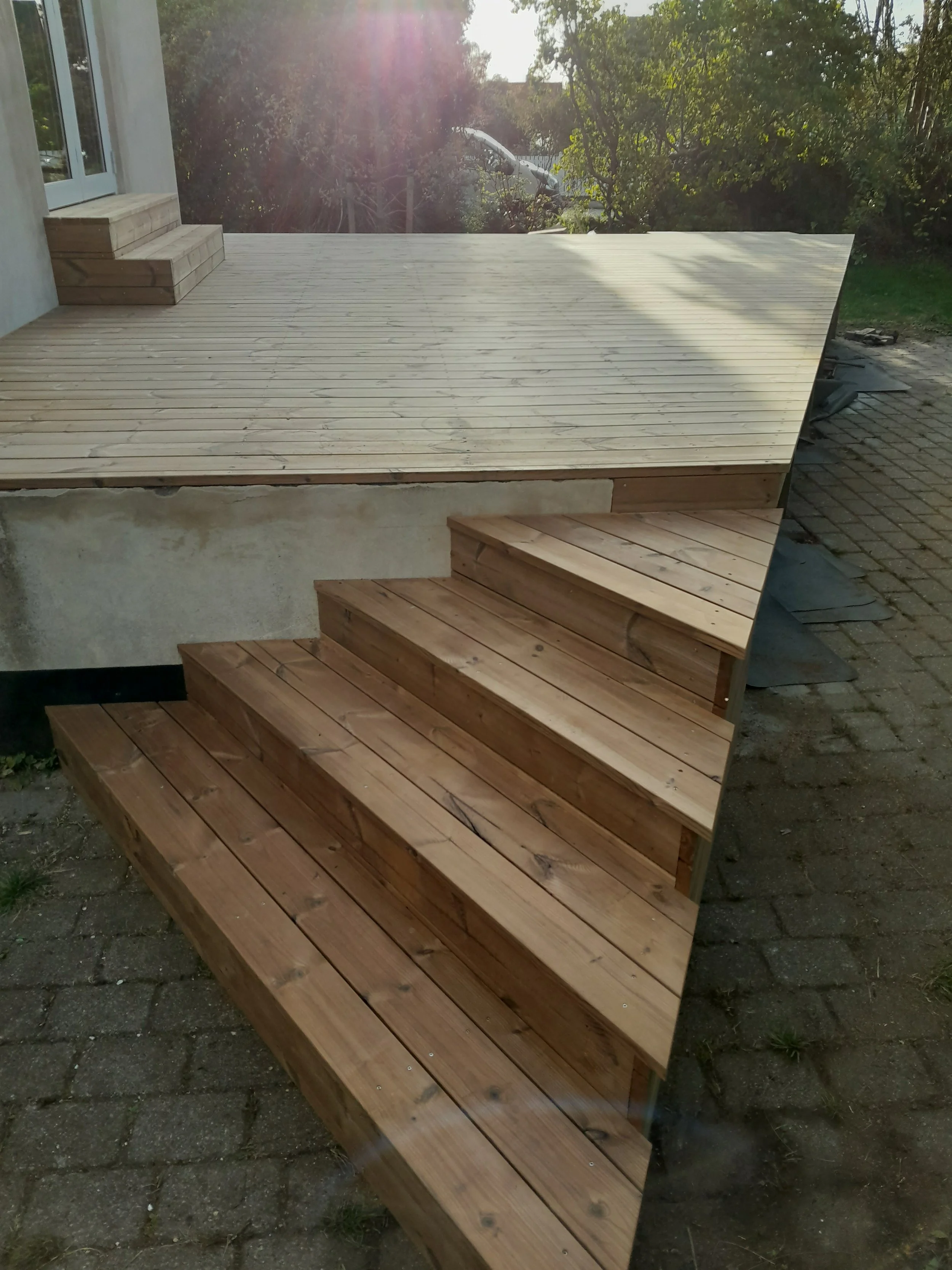 Billedet viser en trappetolder med træplanker, hvor den øverste del er ubehandlet træ og den nederste del er behandlet træ.