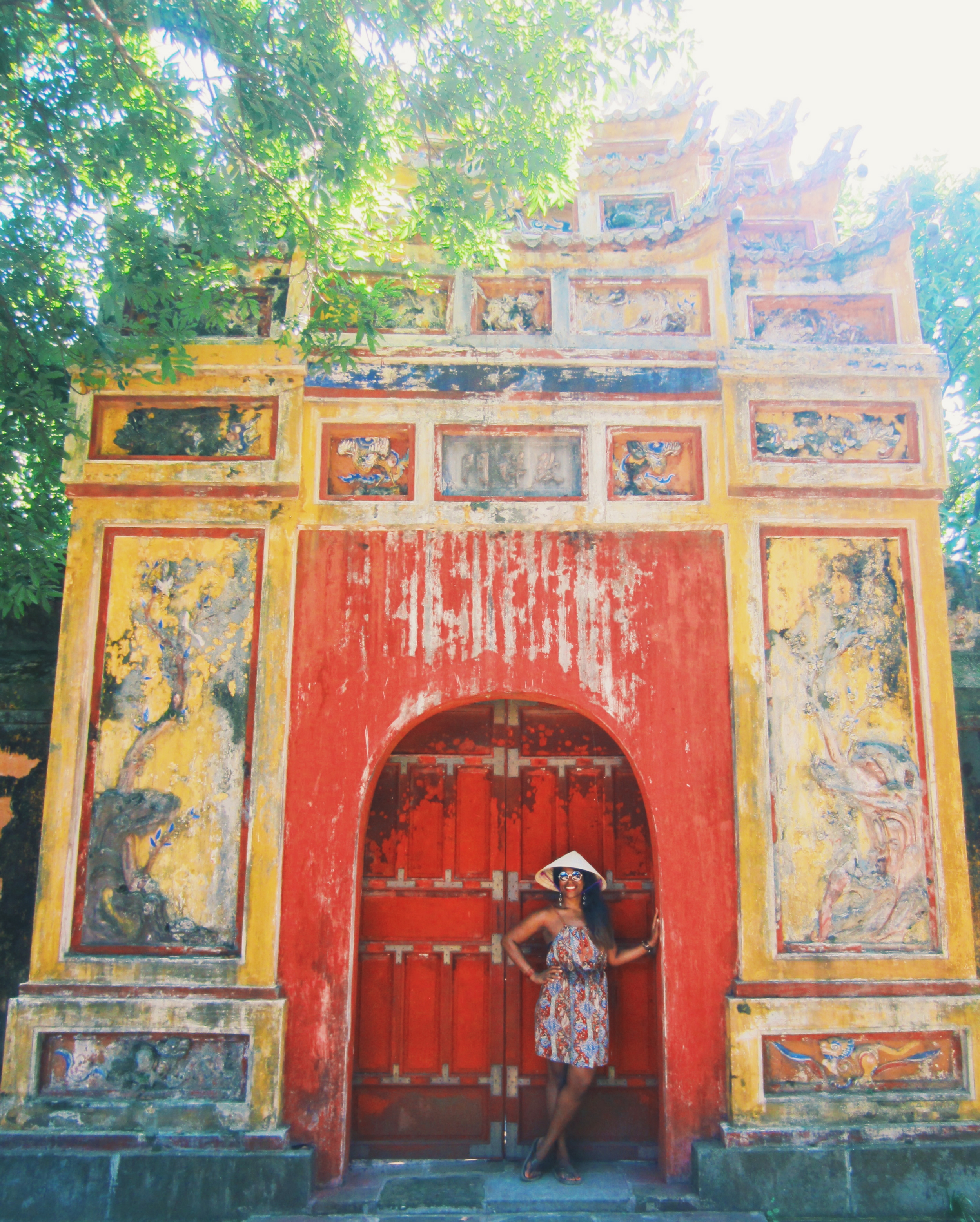 Glo in front of a traditionally decorated door in Hue, Vietnam