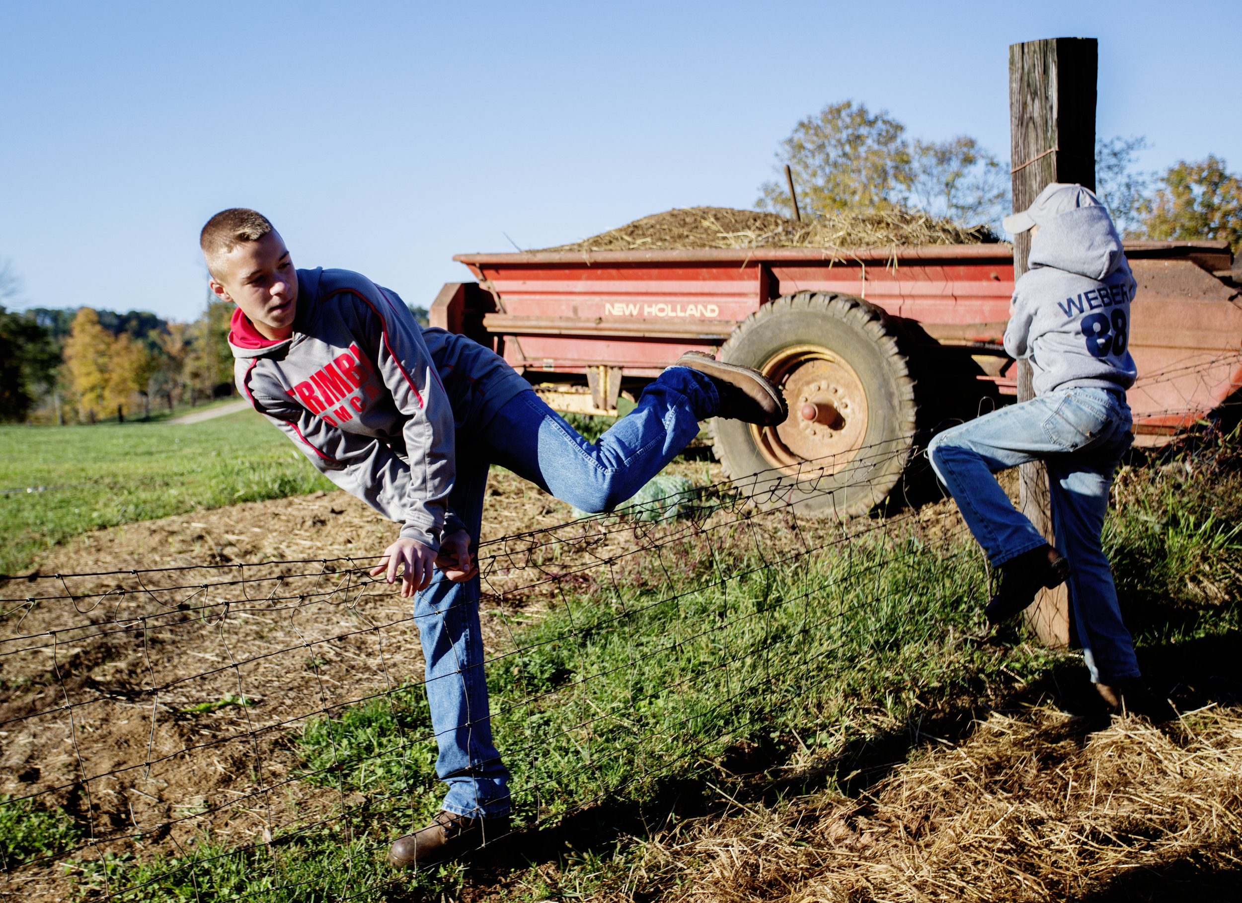  Braden and Levi Weber climb over a fence in their farm yard. 