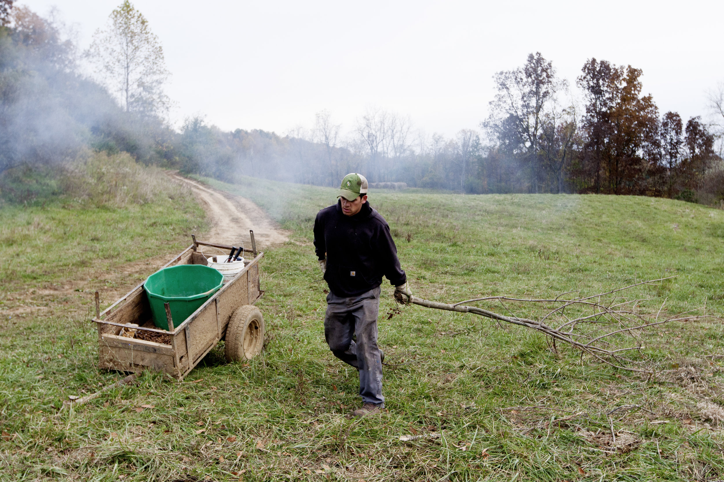  Reitano adds wood and other brush he cut away from a fence line on his farm to a fire.&nbsp; 