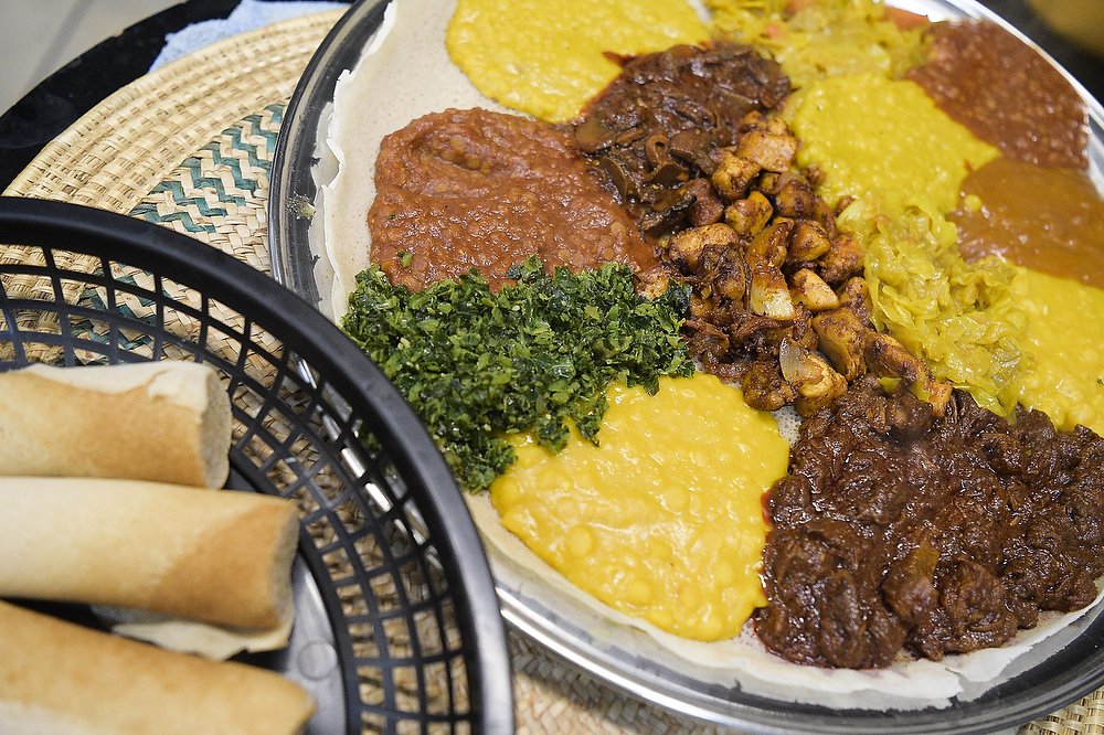  The bountiful "Gosh Combo" features a choice of meats and vegetarian specialties. Ethiopian meals are traditionally served from a communal plate and eaten with the hands. Injera, a flatbread made of teff flour, seen in the bottom left corner, is use