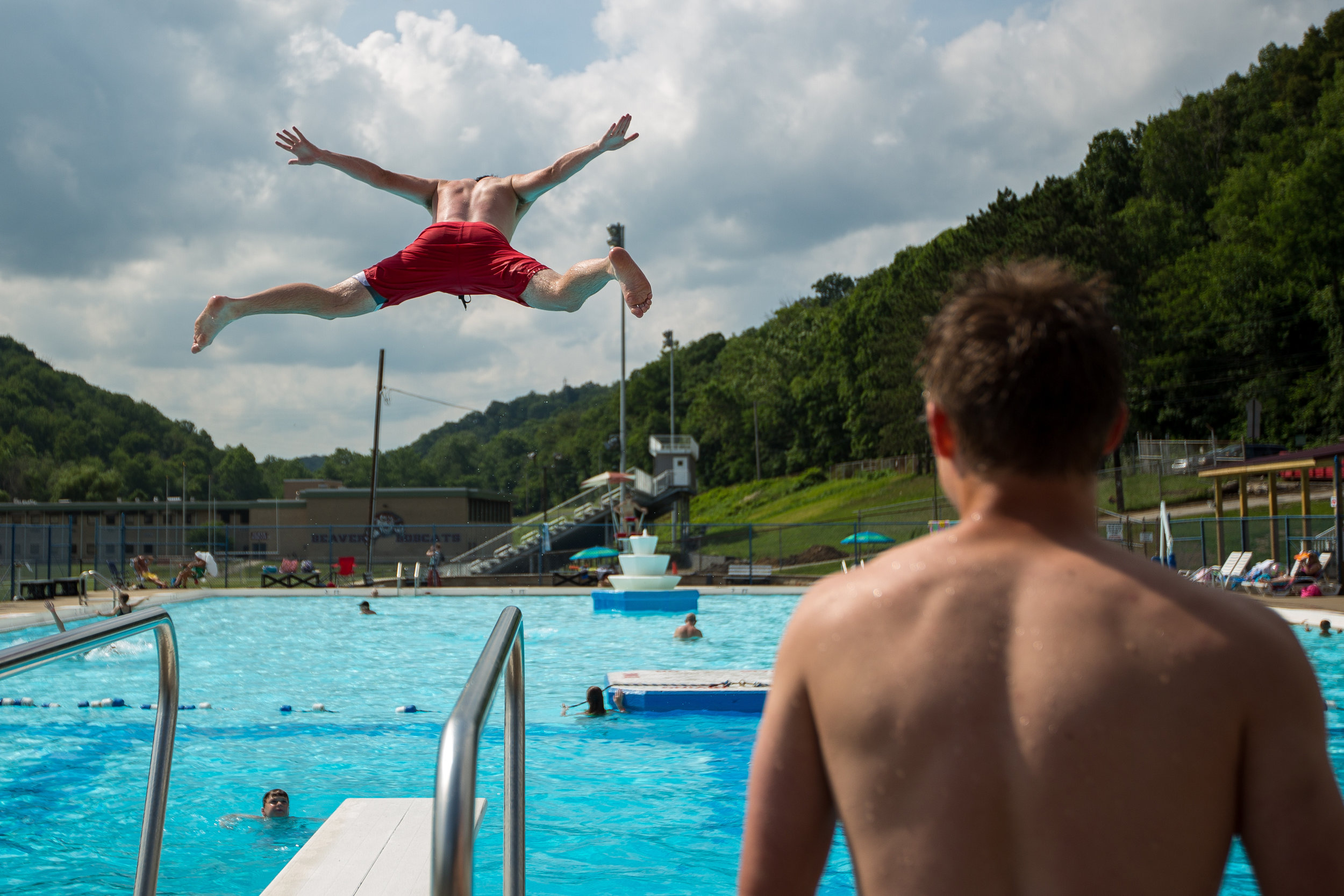  Patrick McGuckin, top left, jumps off of the diving board at the Beaver Pool white friend Zach Logan watches on Thursday afternoon.  