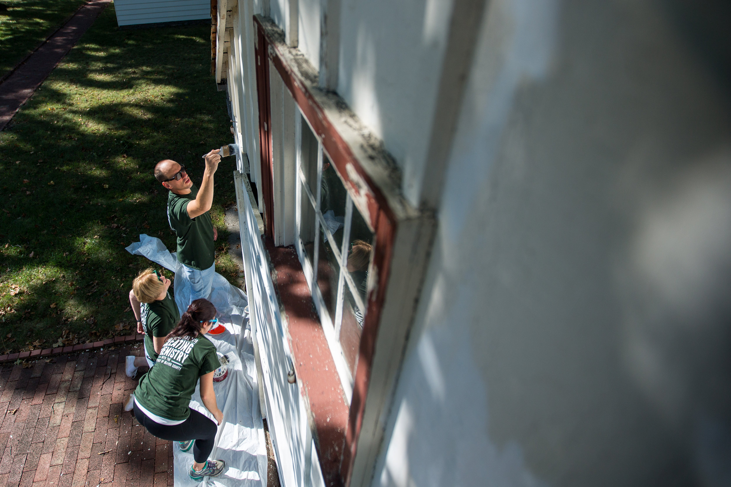  Matt Nosal, top, Susan McMullen and Jamie Telesz work on painting the side of the Blacksmith Shop at Old Economy Village on Wednesday morning. They were part of the United Way of Beaver County Day of Caring, bringing over 100 volunteers together to 