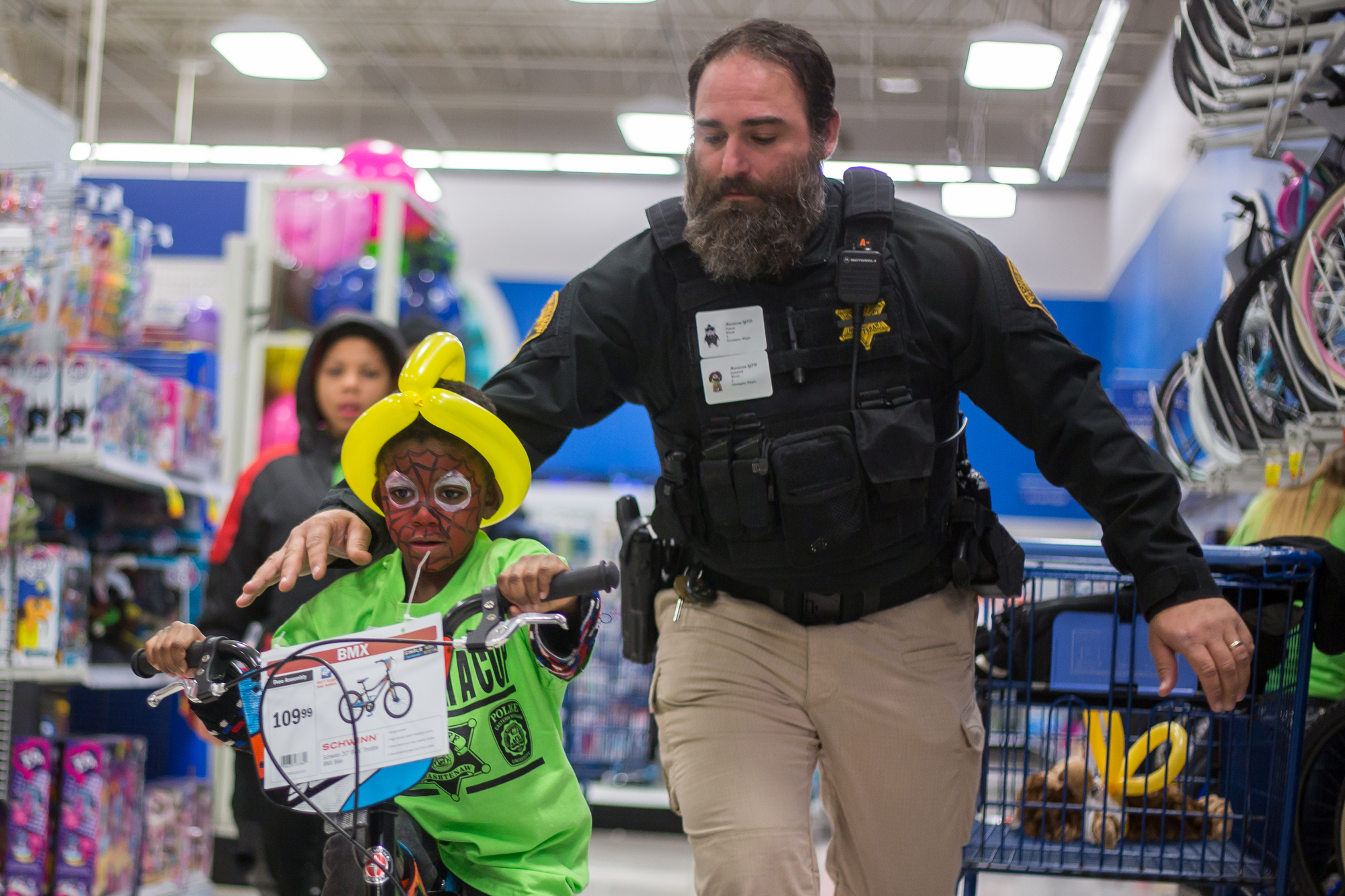  Washtenaw County Sheriff Deputy Buffa pushes Jametrick Woods, 6, on a bike at Meijer in Belleville during the Shop with a Cop on Wednesday, December 7, 2016. The shop with a Cop program paired 100 children with about 120 local police officers, sheri