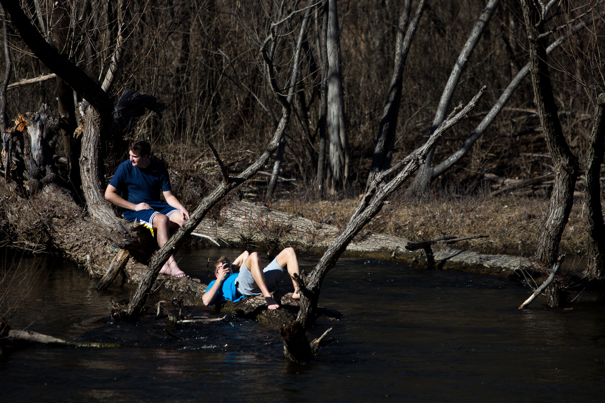  Two individuals sit on a log near the Huron River while at Nichols Arboretum on Saturday, February 18, 2017. According to the National Weather Service, Saturday's high was nearly 58 degrees and locals took advantage of the above average temperatures