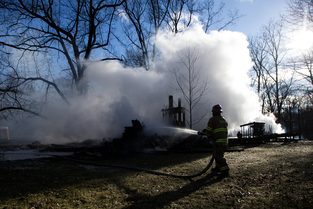  A Dexter area fire fighter sprays water onto a hot spot during a structure fire on Scully Road in Webster Township on Friday, March 10, 2017. The fire completely destroyed the home and a nearby field caught on fire. The cause of the fire is still un