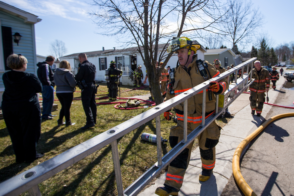  A fire fighter walks a ladder back to a fire truck after extinguishing a fire at a mobile home in Scio Farm Estates that caught fire on Thursday, March 23, 2017. The cause of the fire is under investigation. Matt Weigand | The Ann Arbor News 