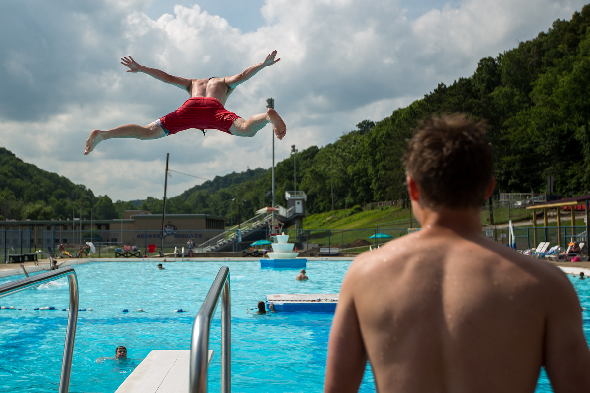  Patrick McGuckin, top left, jumps off of the diving board at the Beaver Pool white friend Zach Logan watches on Thursday July 7, 2016.  