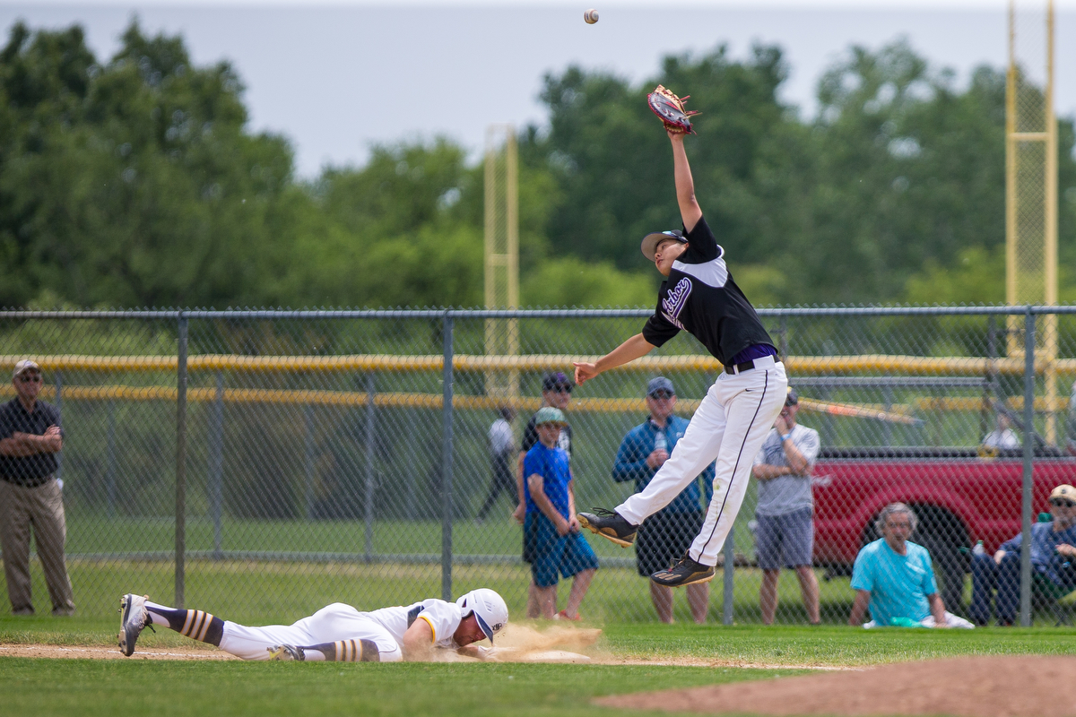  A Pioneer first baseman jumps for the ball as Saline's Jacob Finkbeiner (10) slides to touch first base during the district semi finals at Saline High School on Saturday, June 3, 2017. Saline beat the Pioneer 5-1. Matt Weigand | The Ann Arbor News 