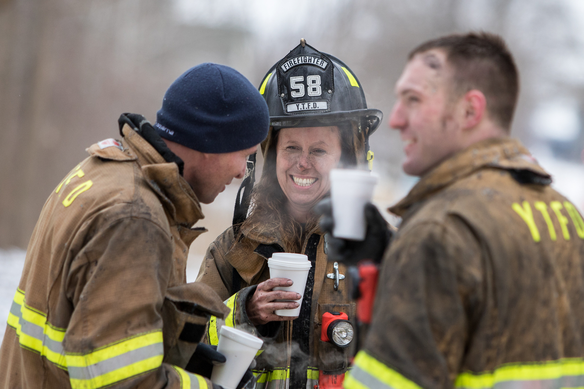  Maryanne Cleaver of the Ypsilanti Township Fire Department smiles with colleagues while drinking coffee after extinguishing a house fire at 9525 East Bemis Road in Ypsilanti Township on Sunday, January 29, 2017. The fire, which is still under invest