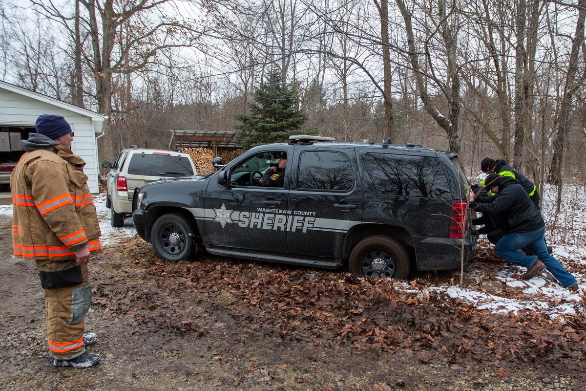  Employees of Belfor property restoration help push out a sheriff's patrol car after it got stuck in the mud after Ypsilanti Township fire fighters after extinguishing a house fire at 9525 East Bemis Road in Ypsilanti Township on Sunday, January 29, 