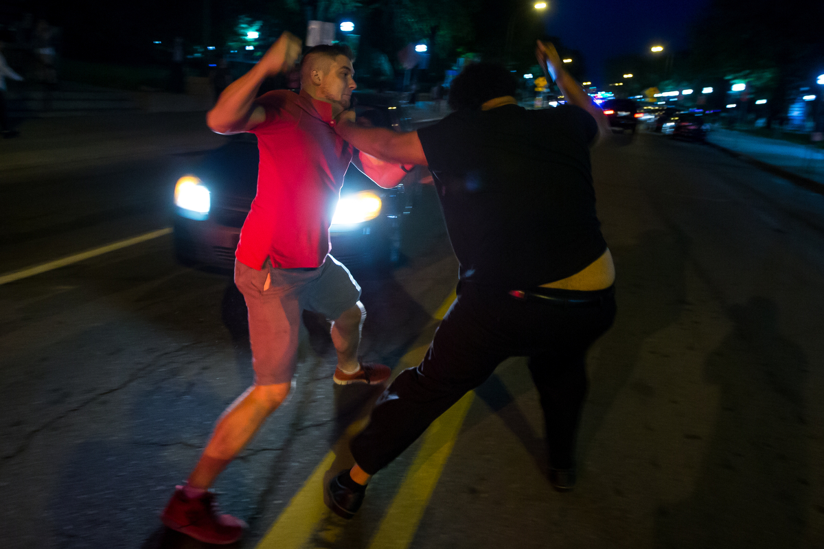  A University of Michigan sophomore, black shirt, fights with an individual, red shirt, while a group of protesters block the intersection of State Street and South University Street on Wednesday, September 20, 2017. The group organized at the Michig