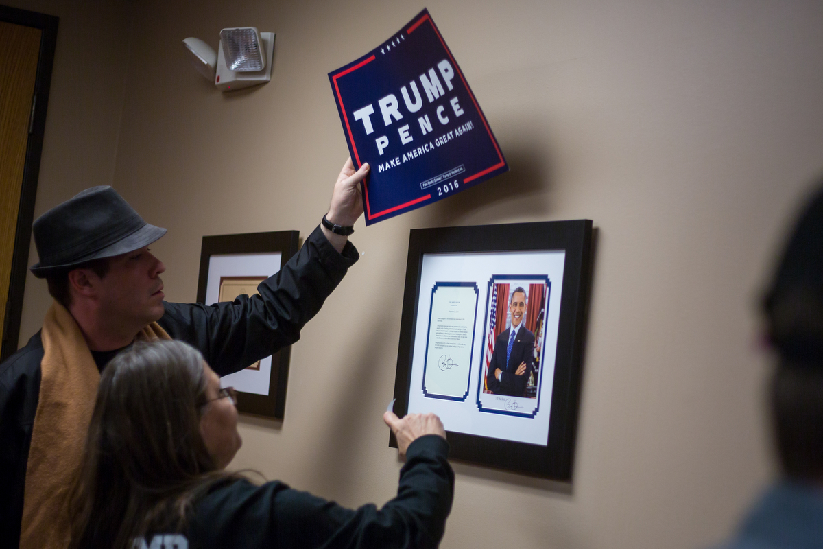  Deborah Fuqua-Frey, right and a man who did not disclose his name place a Donald Trump sign over a picture and letter form President Obama at the Washtenaw County Republicans watch party at the National Center for Manufacturing Sciences building on 