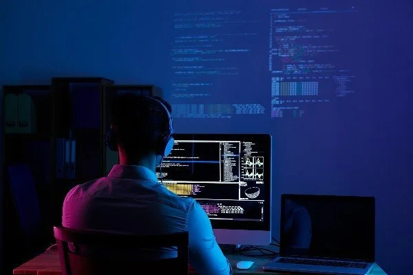 man working in a dark room at a computer