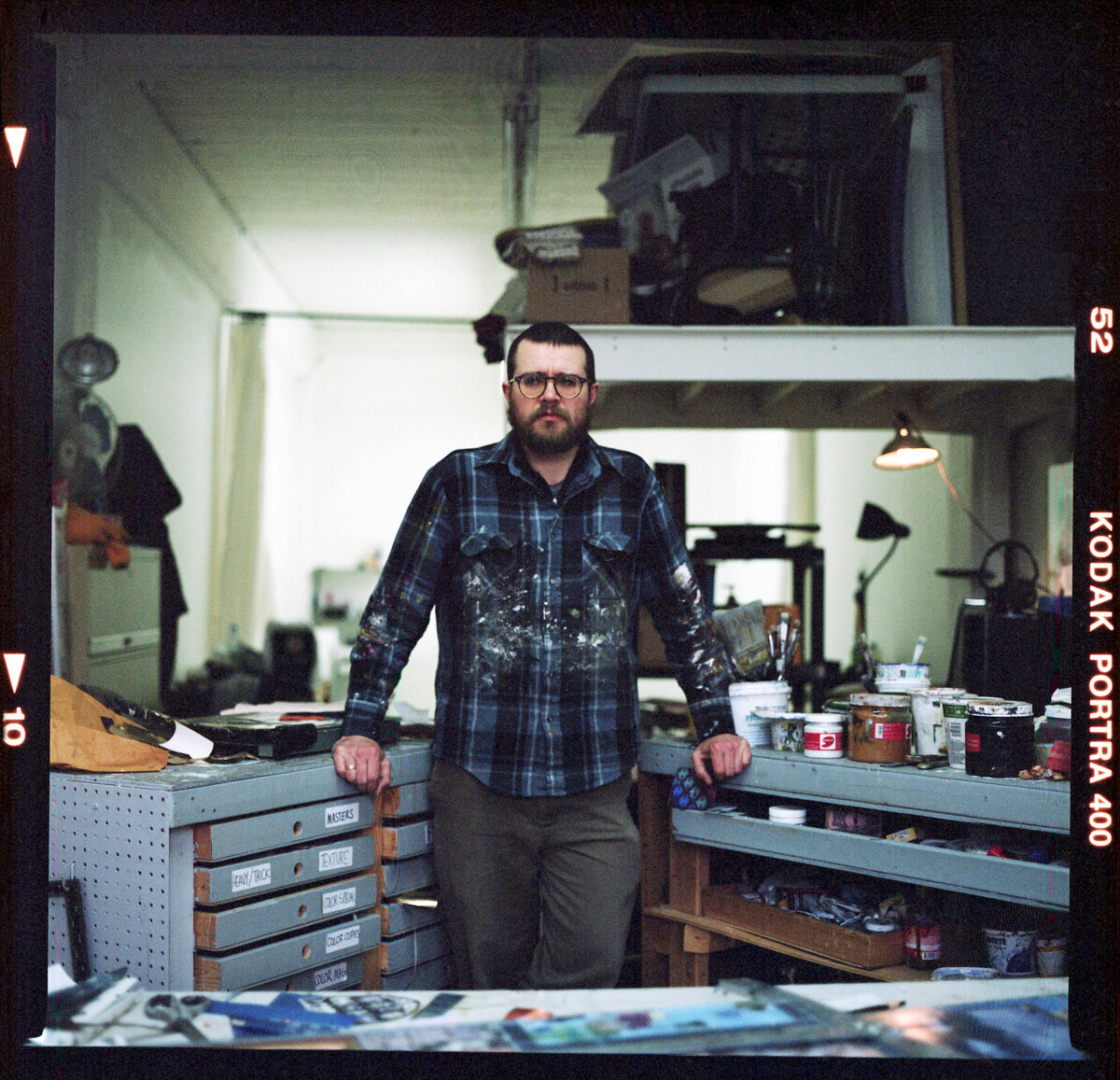 Visually impaired mixed media artist Gavin Sewell stands surrounded by his supplies of collage papers, paints, and brushes in his Montréal studio.