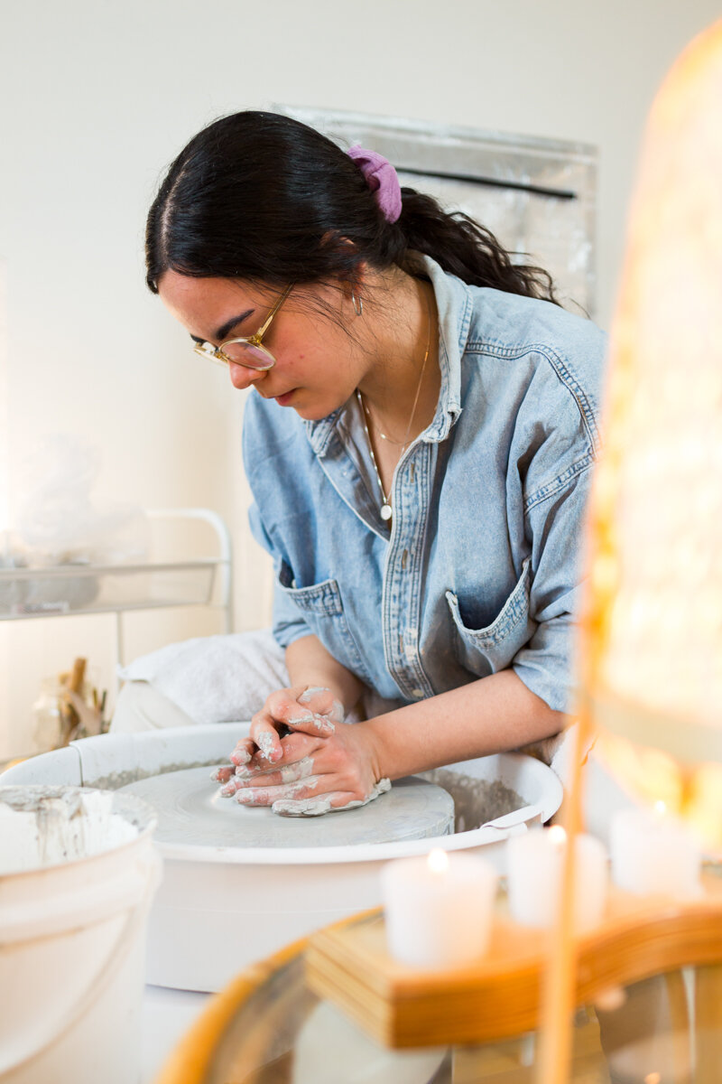 Ceramist Hashmita Alimchandani forms a clay cup on a pottery wheel using gray stoneware clay in her home studio in Montréal, Canada.