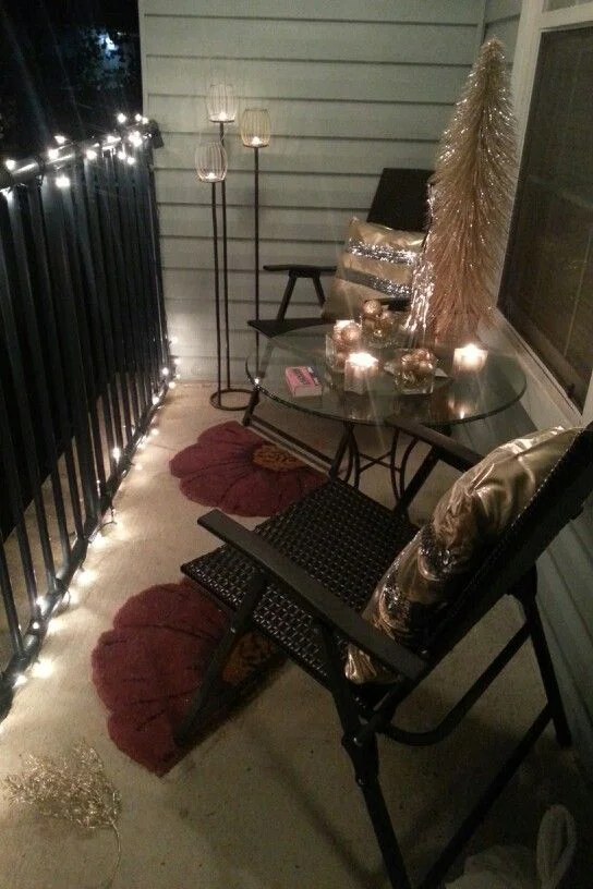 See? Hanging lights on the metal railing adds a homey touch to any space. This patio features doormats as personal rugs for each chair and the golden touches glisten with each lit candle (OK, it's possible this might be a rustic holiday-themed patio... But you can do this with daisies and sunflowers and any bright colors that make you feel like summer has arrived).
