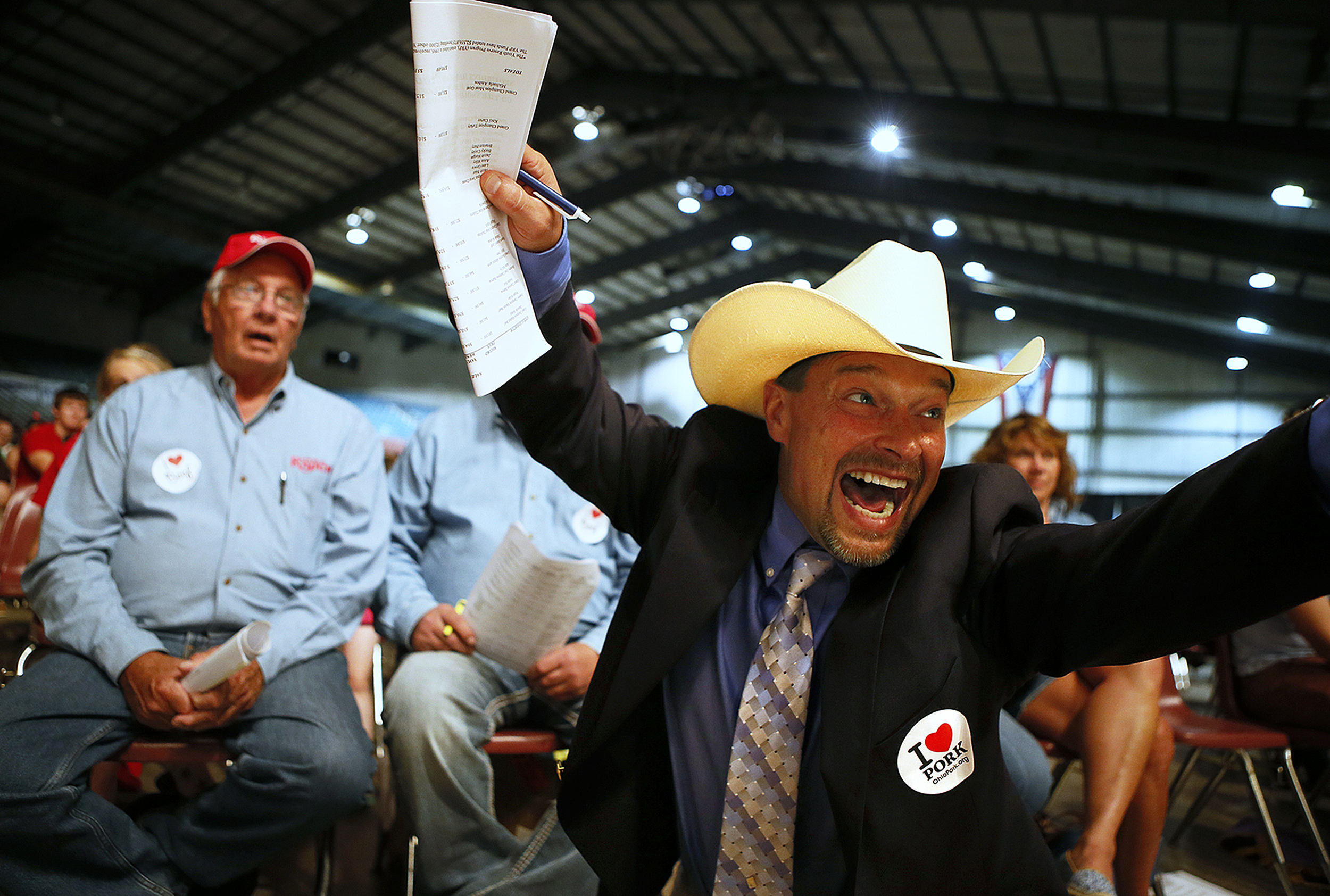 Auctioneer Todd Woodruff shouts and waves his arms wildly after Steve Rausch and Associates bid the high price of 80,000 dollars for the grand champion market steer at the Sale of Champions, Sunday, August 3, 2014, in the Celeste Center at the Ohio State Fair.