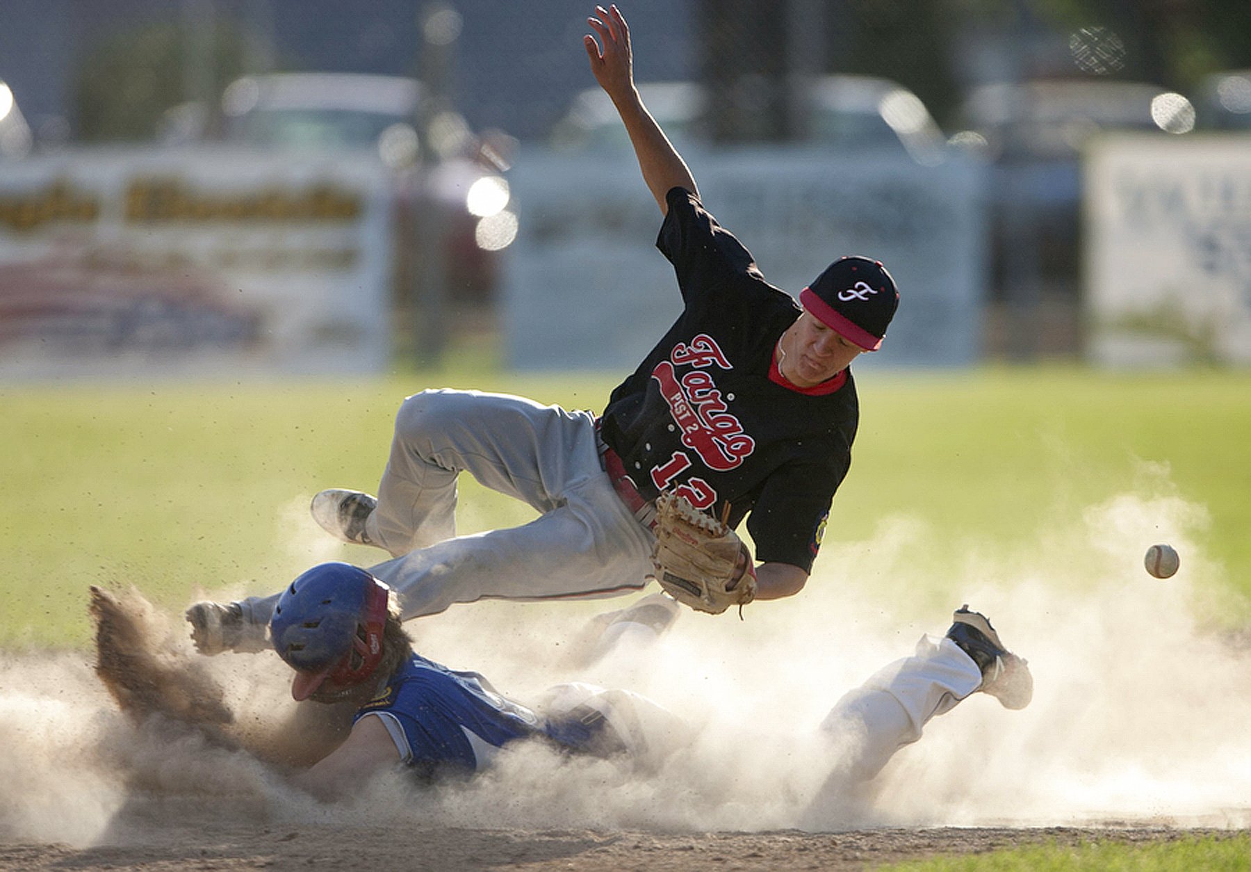  Fargo shortstop Jake Salentine dives for a catch in attempt to tag East Grand Forks' Hunter Aubol, as he slides safely into second base during the game at Stauss Field Thursday evening. East Grand Forks Legion Post 157 lost to Fargo Legion Post 2, w