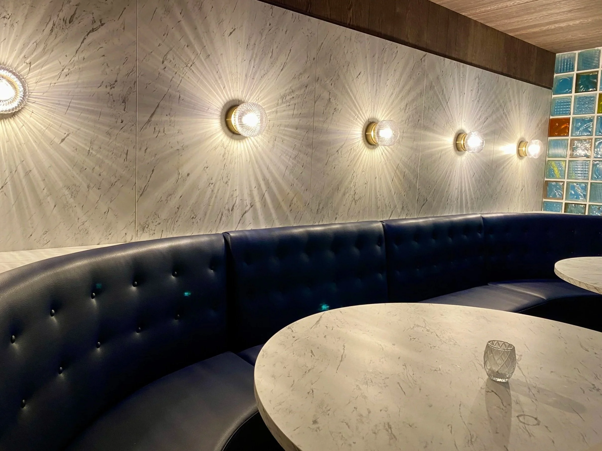 The blue zone has a different vibe - a large curved booth, perfect for larger groups, elevated with a mid-century aesthetic and classy lighting.