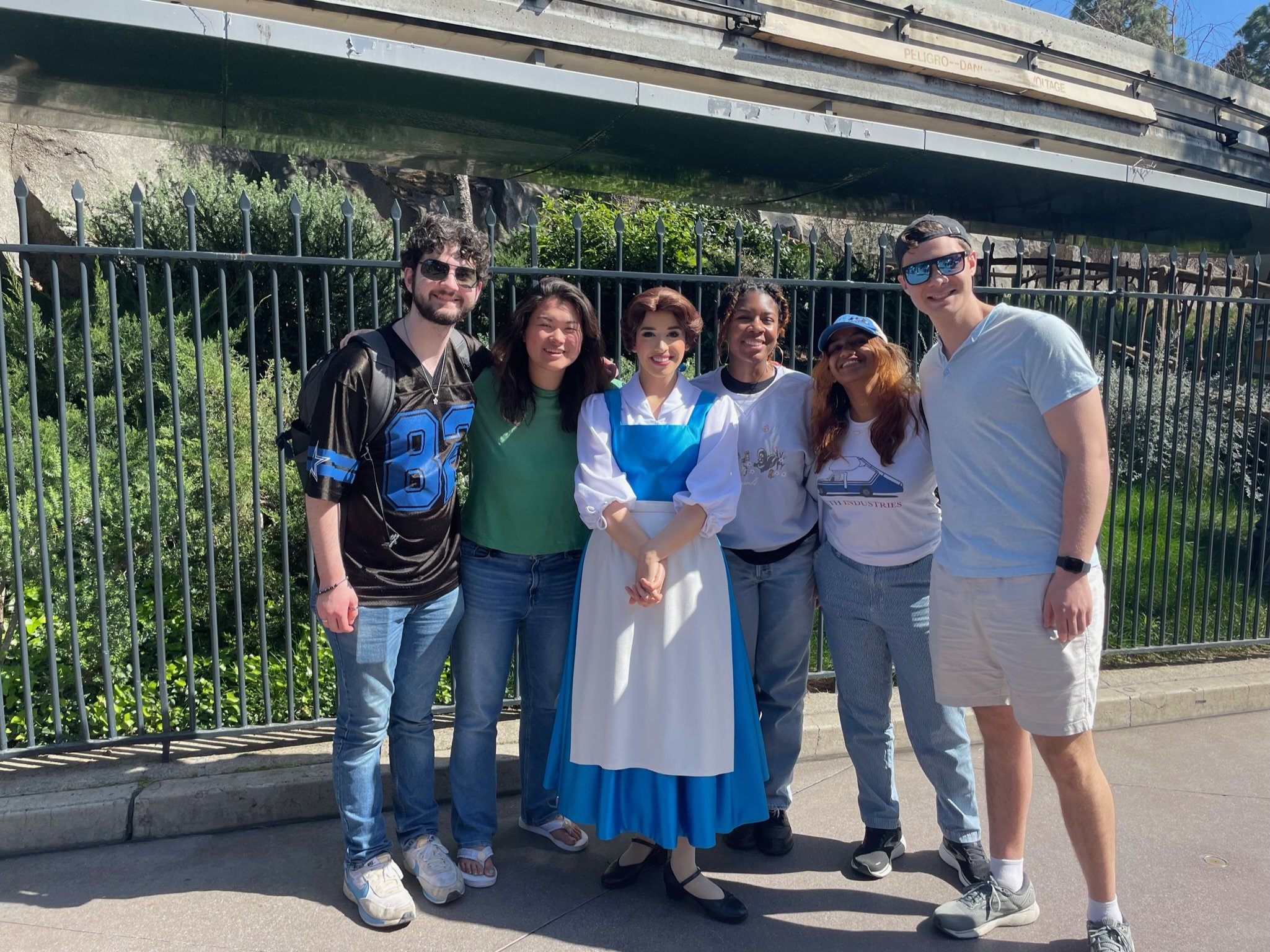  (Left to right) Will, Mary Ben, Misan, Rishika, and Ian standing with Belle in Disneyland.  