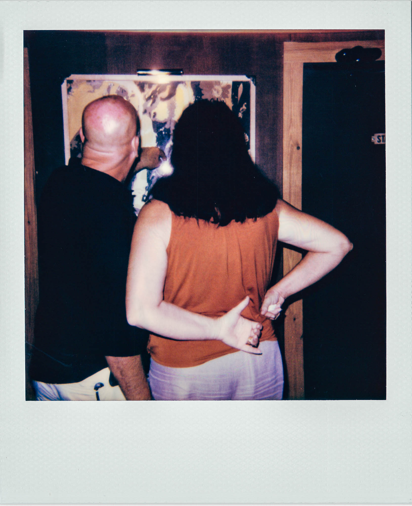 Couple looking at print of nude ladies at Wallys Mills Avenue Liquors