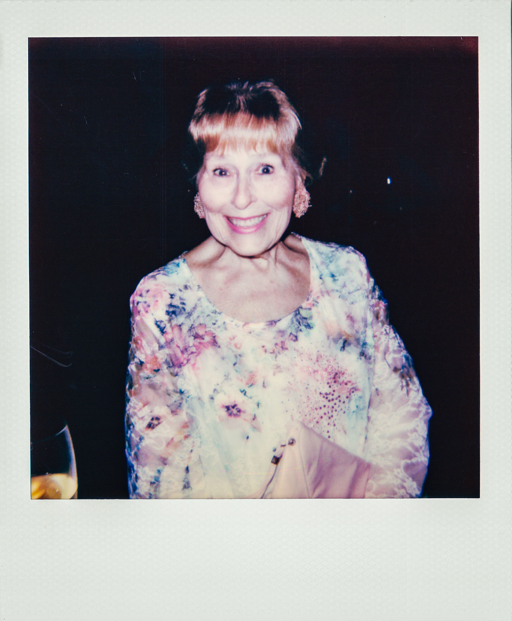 Linda Updike smiling next to a glass of wine at Wallys Mills Avenue Liquors