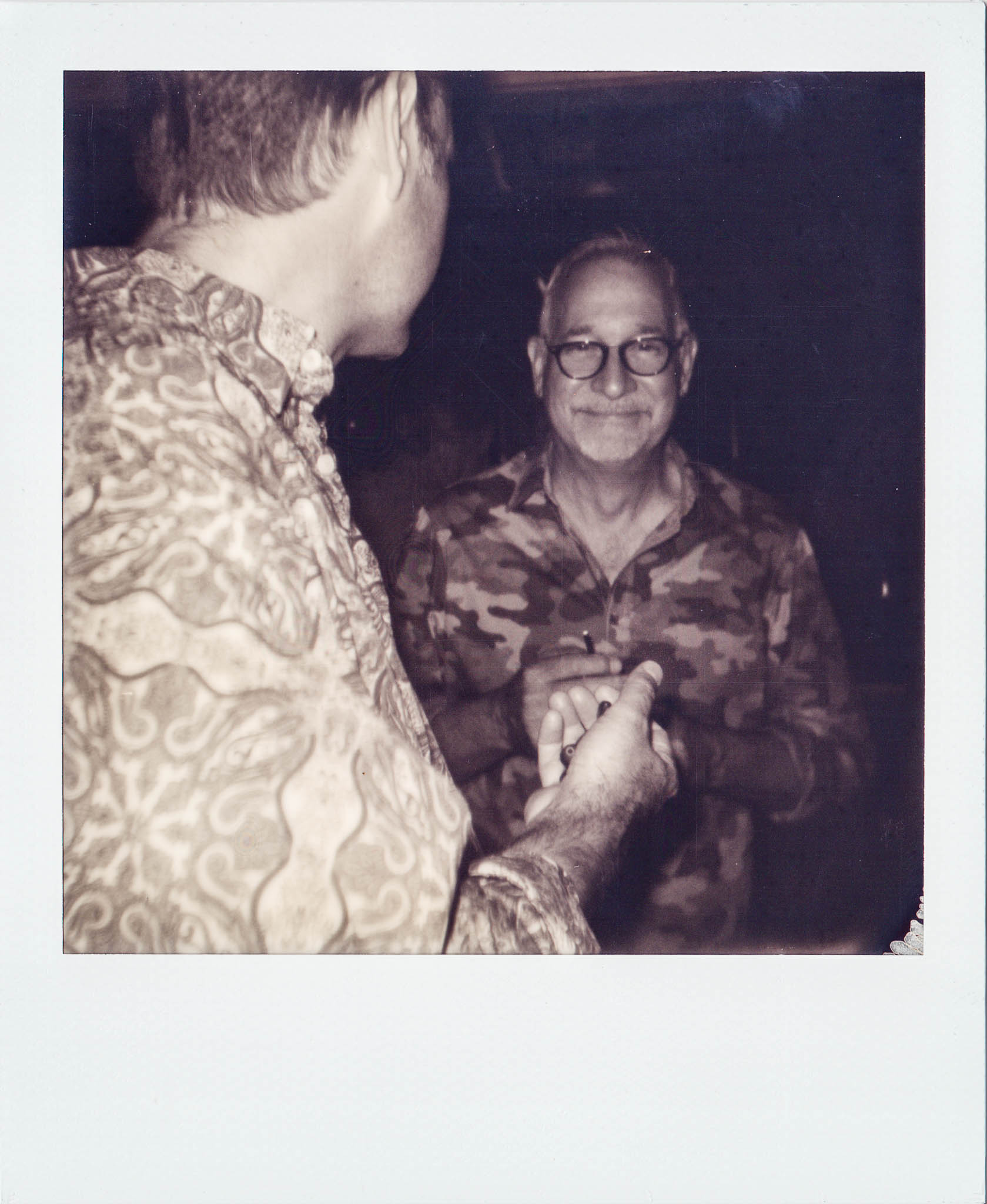 A man with a drink in his hand talking with designer Reid Pasternak at Wallys Mills Avenue Liquors