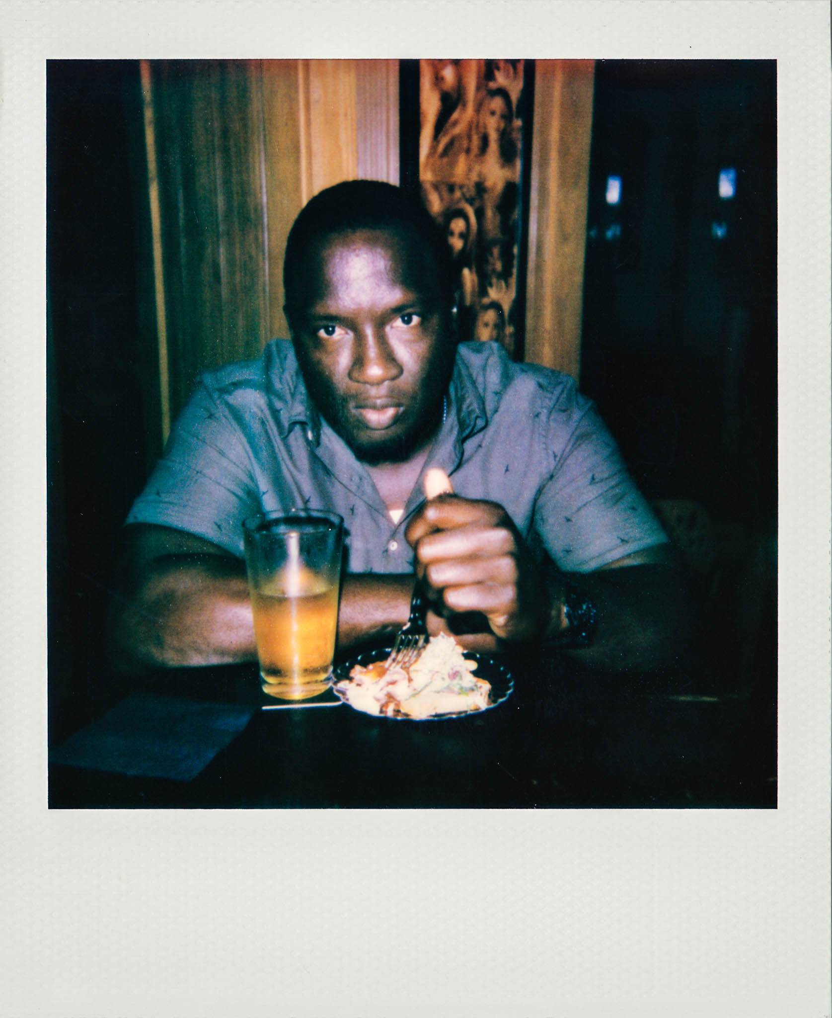 A man staring at the camera while eating and drinking at Wallys Mills Avenue Liquors