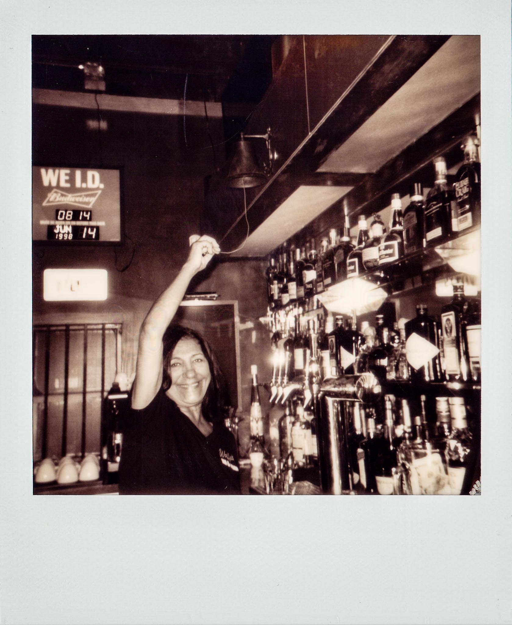 Cindy the bartender ringing the bell at Wallys Mills Avenue Liquors