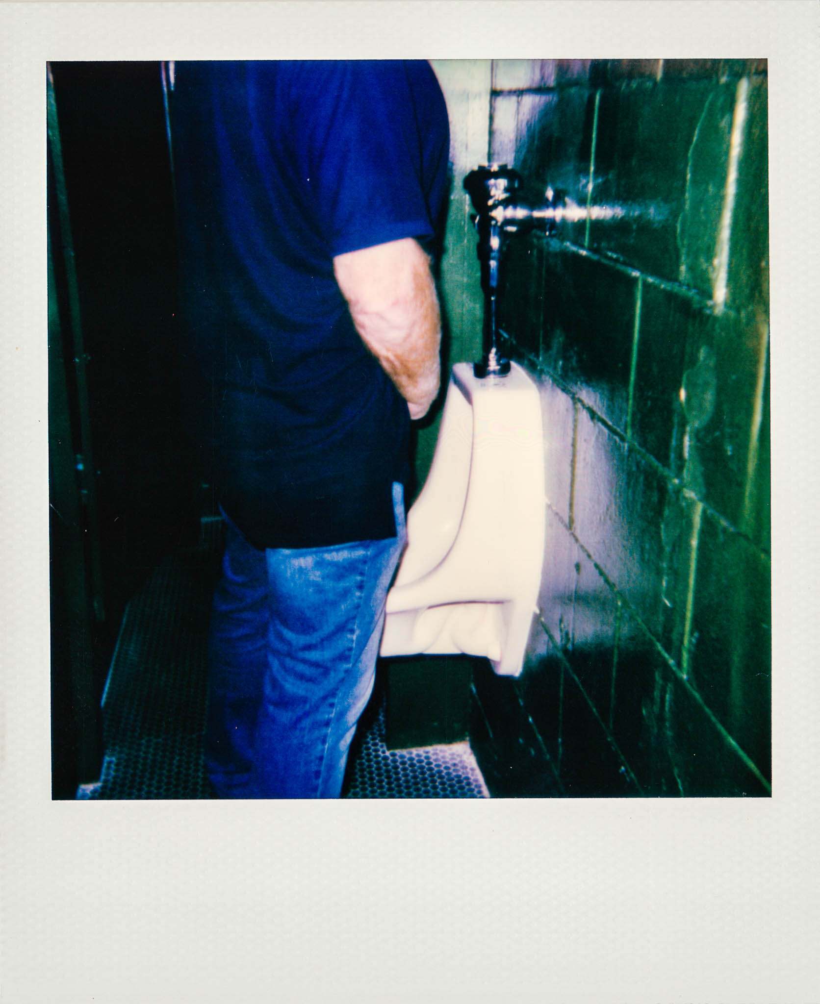 Man peeing in urinal at Wallys Mills Avenue Liquors