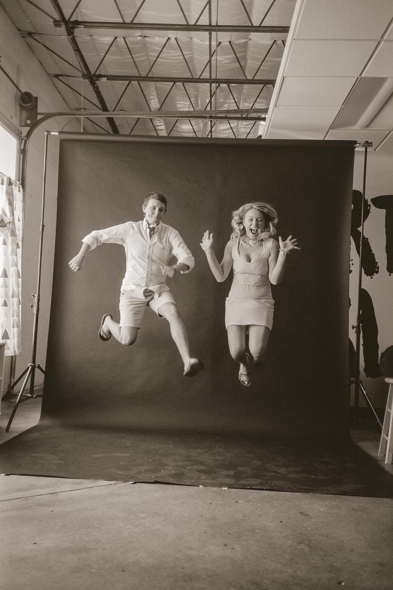 Guy and girl jumping in front of a studio backdrop