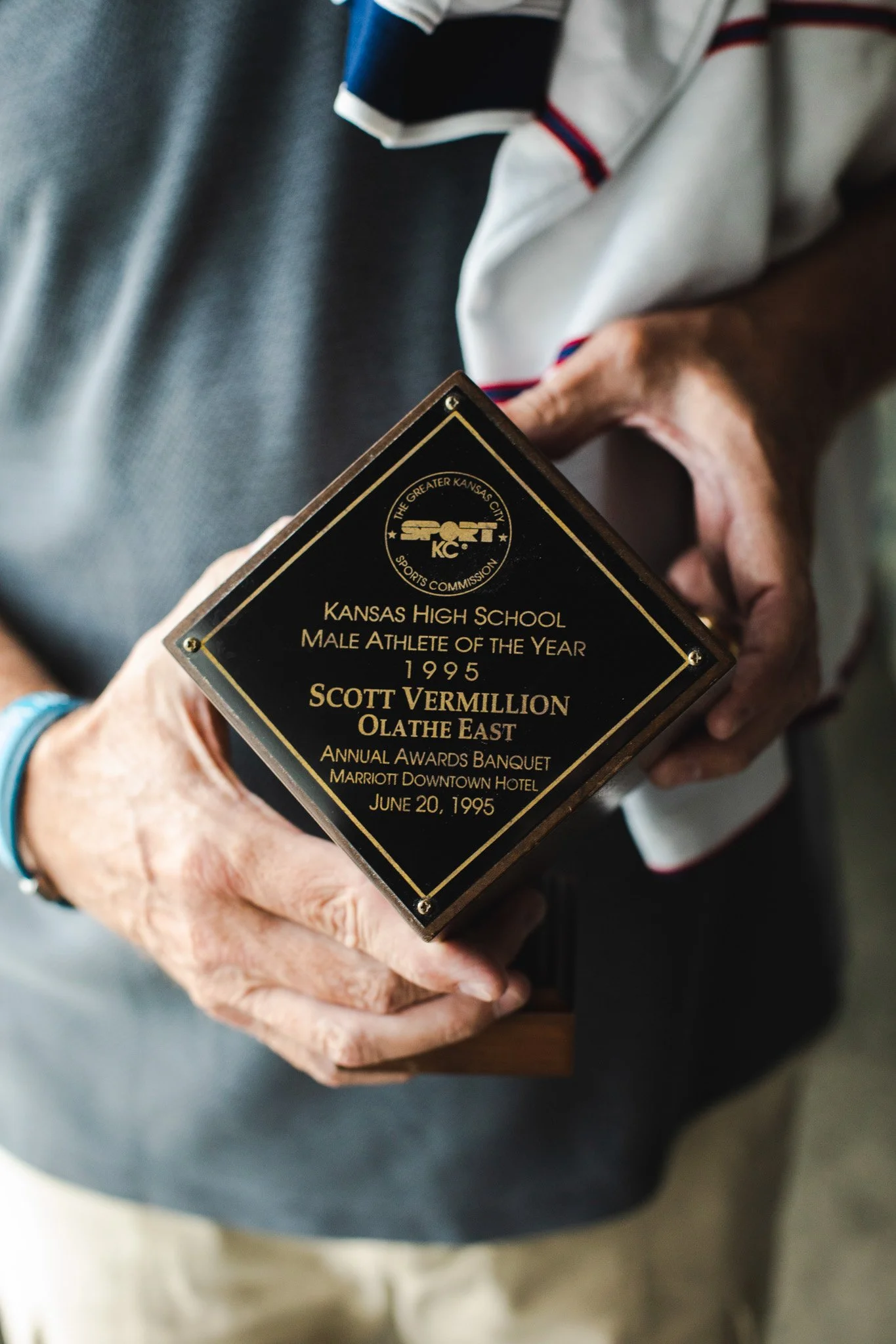 Close-up of a person's hands holding a black and gold plaque awarded to Scott Vermillion for Kansas High School Male Athlete of the Year, 1995, at the annual awards banquet at the Marriott Downtown Hotel on June 20, 1995.