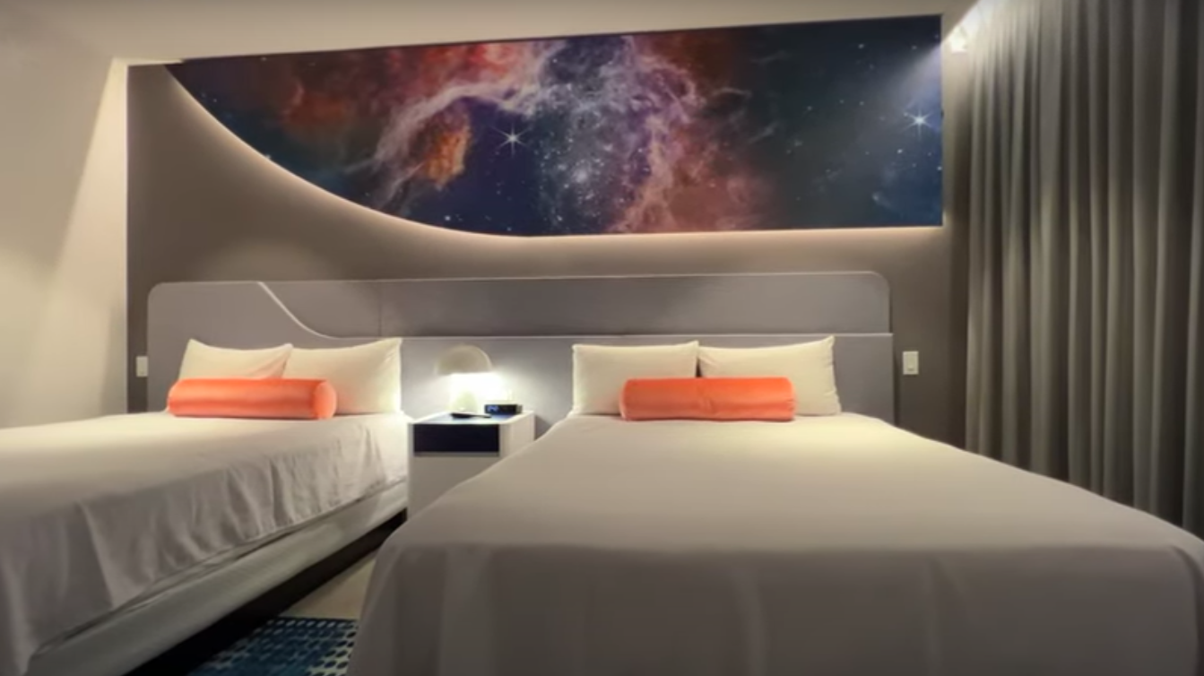 stella nove resort room with 2 queen beds and a cosmic mural on wall
