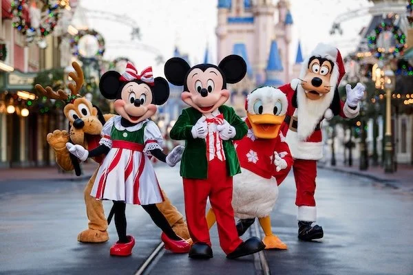 Mickey mouse, minnie mouse, donald duck, and goofy dressed in christmas attire at magic kingdom park.