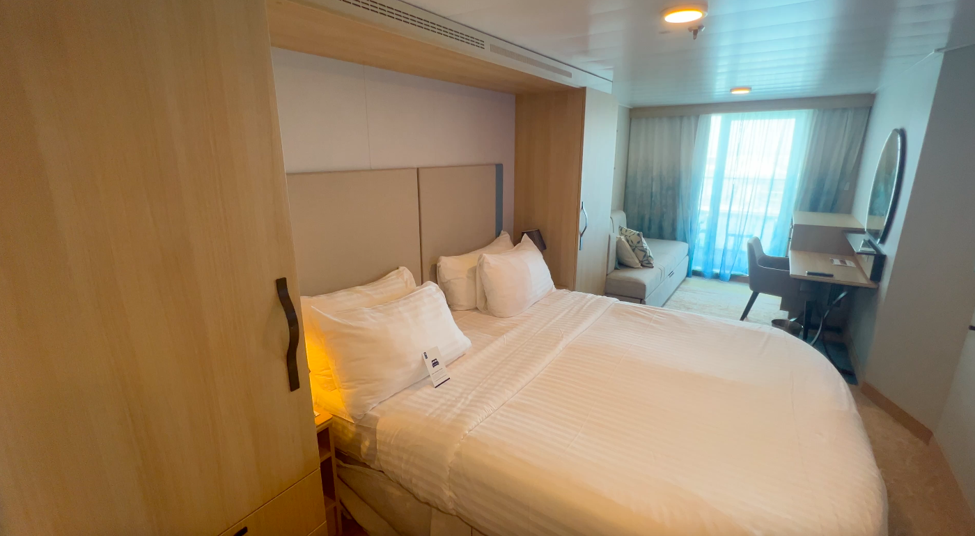 Wonder of the Seas stateroom showing a bed, sofa, and balcony