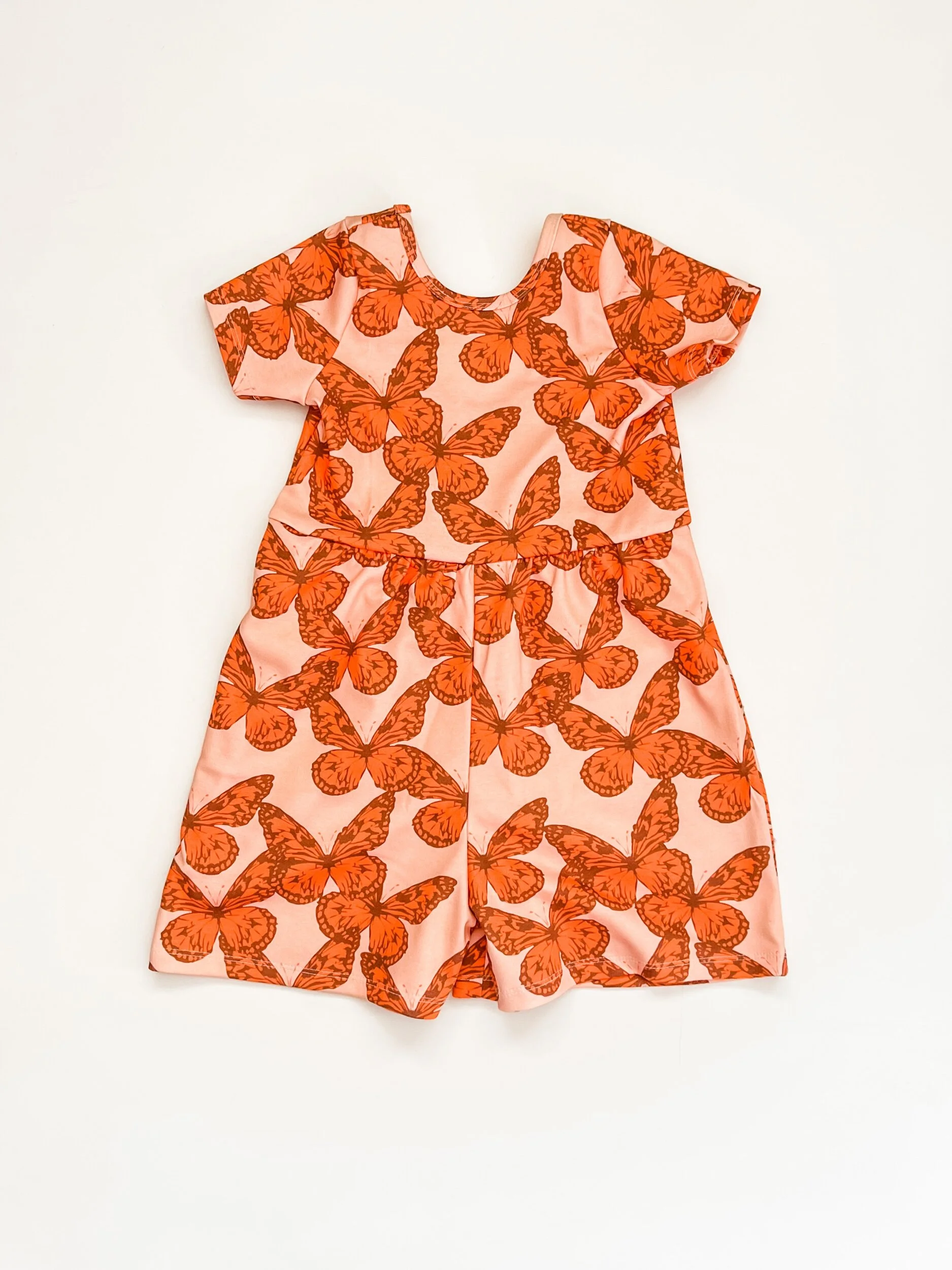 scoop back romper in pink with orange butterflies