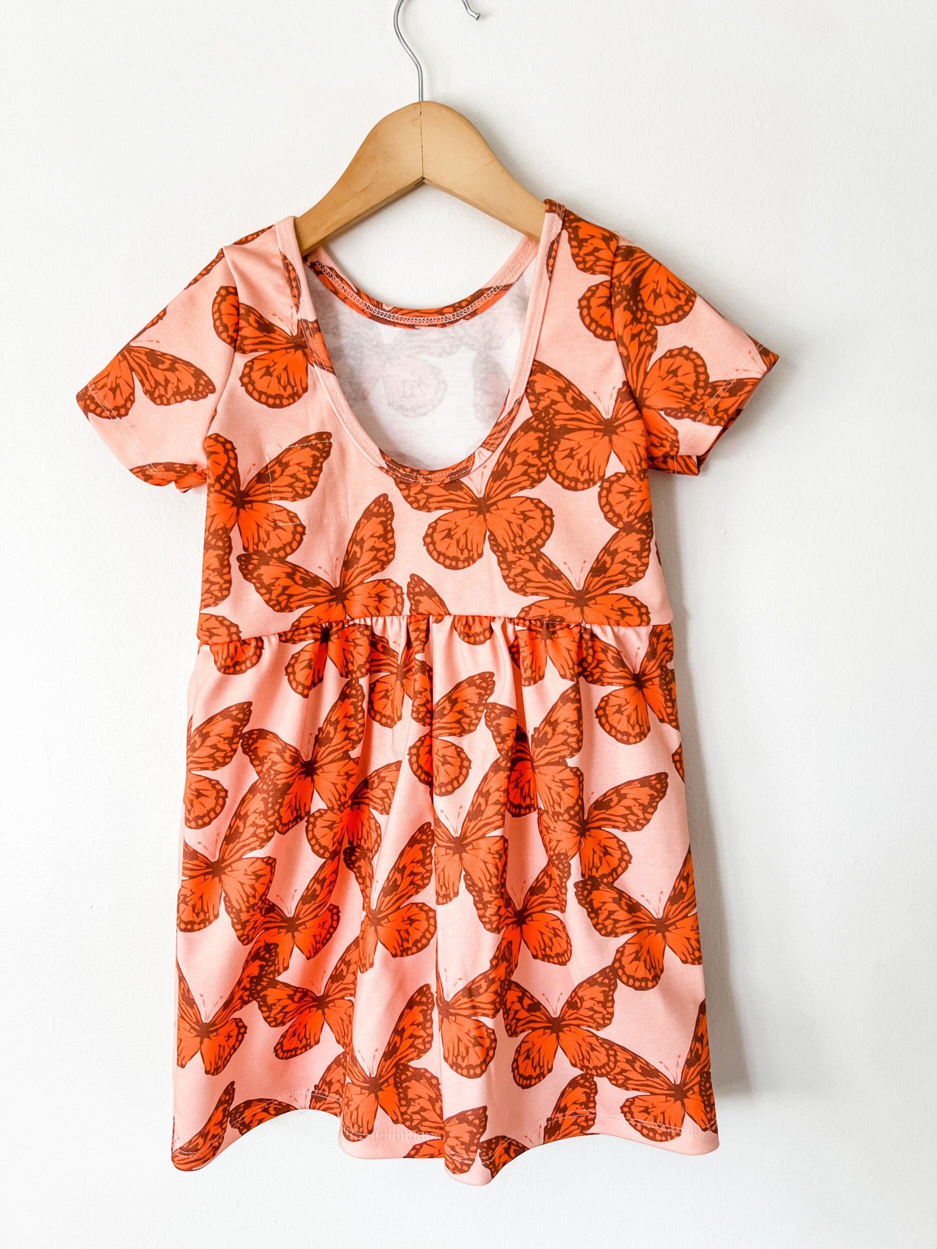 scoop back romper in pink with orange butterflies