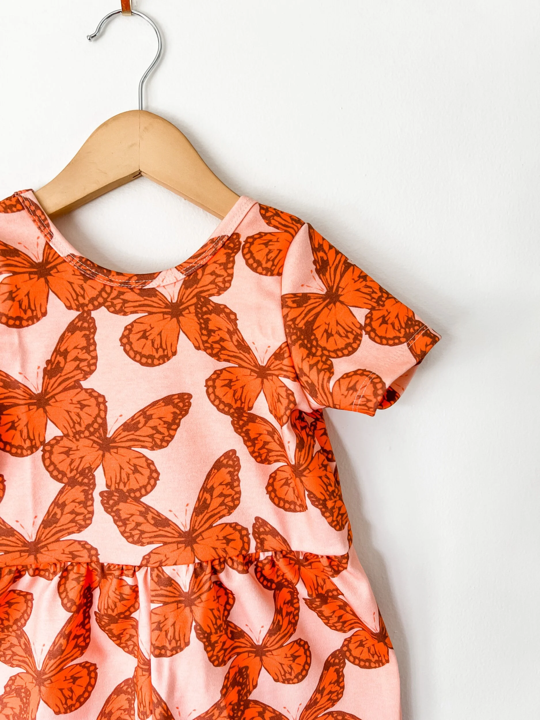 scoop back romper in pink with orange butterflies