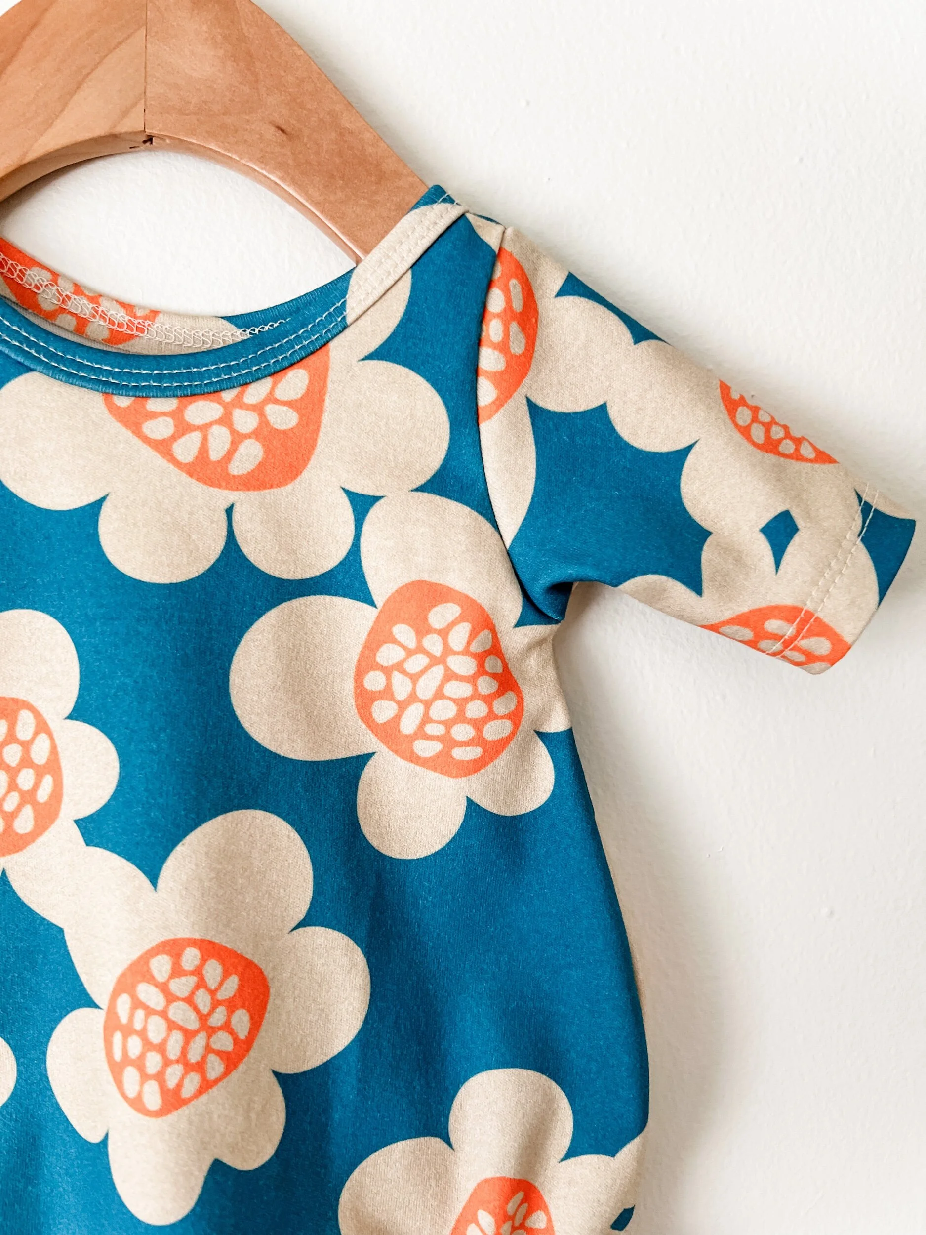 baby bubble romper with blue background and cream and orange flowers