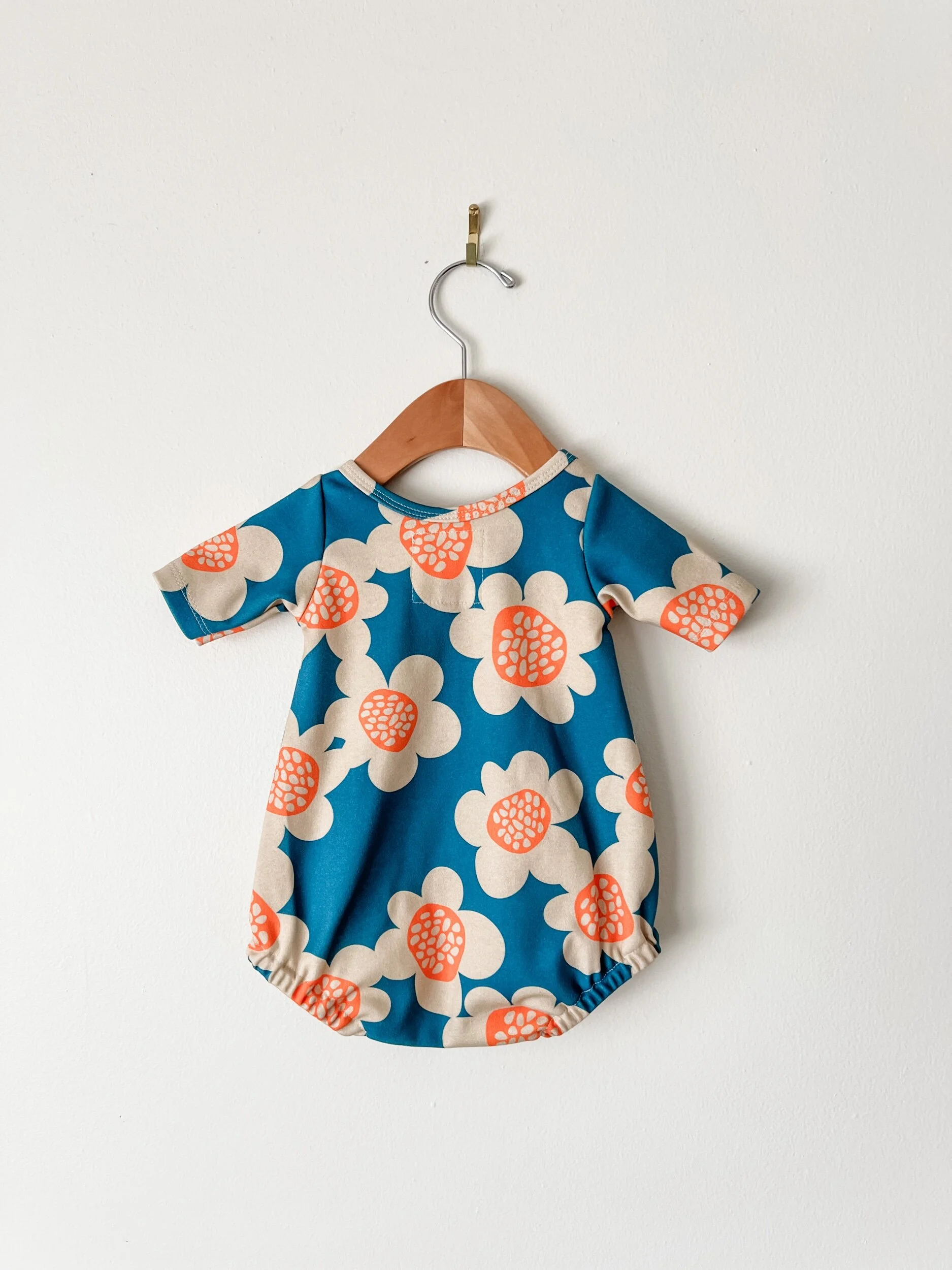baby bubble romper with blue background and cream and orange flowers