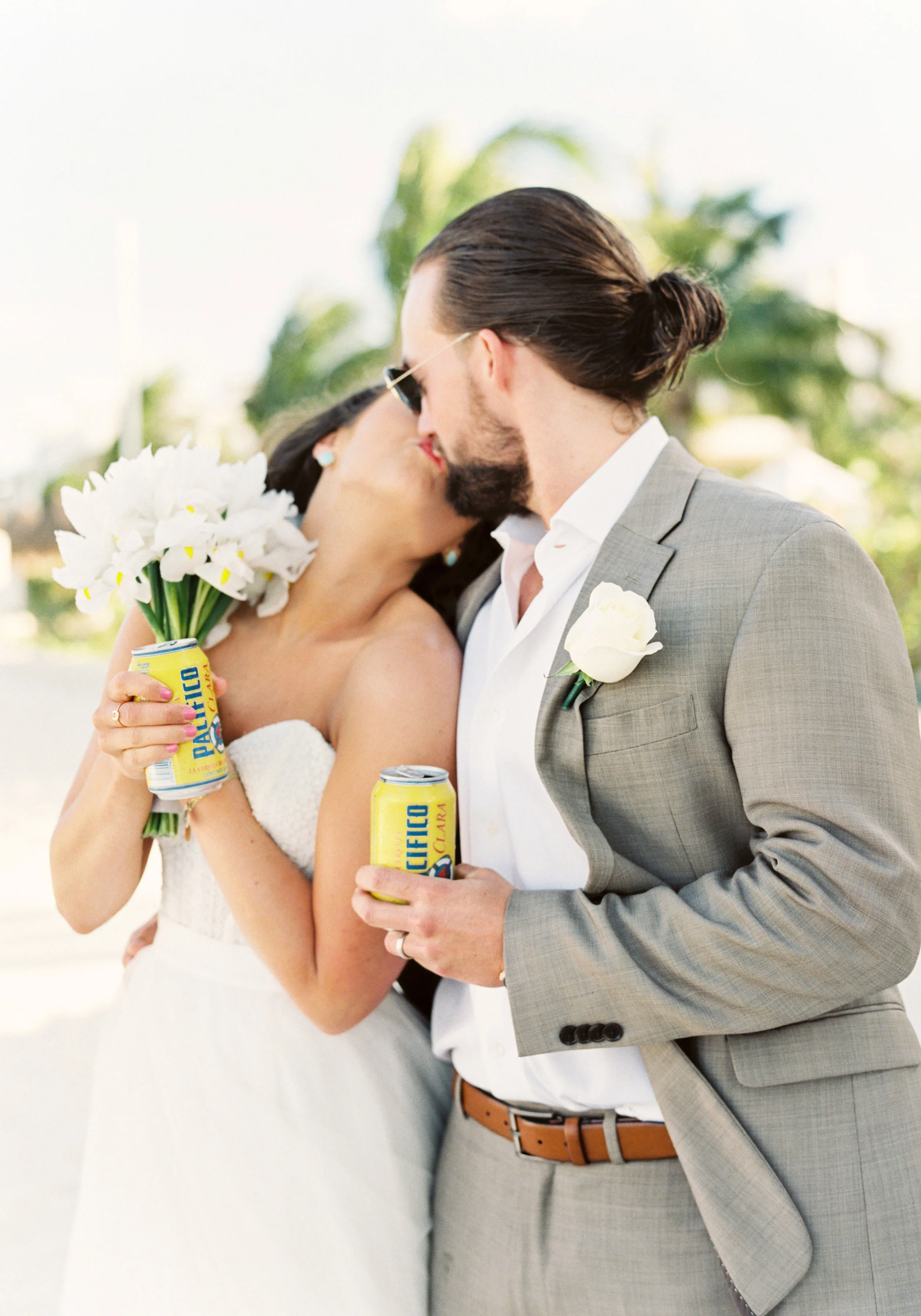 Destination wedding in Mexico, beach wedding, bride and groom at cocktail hour on the beach. Groom with a man bun.